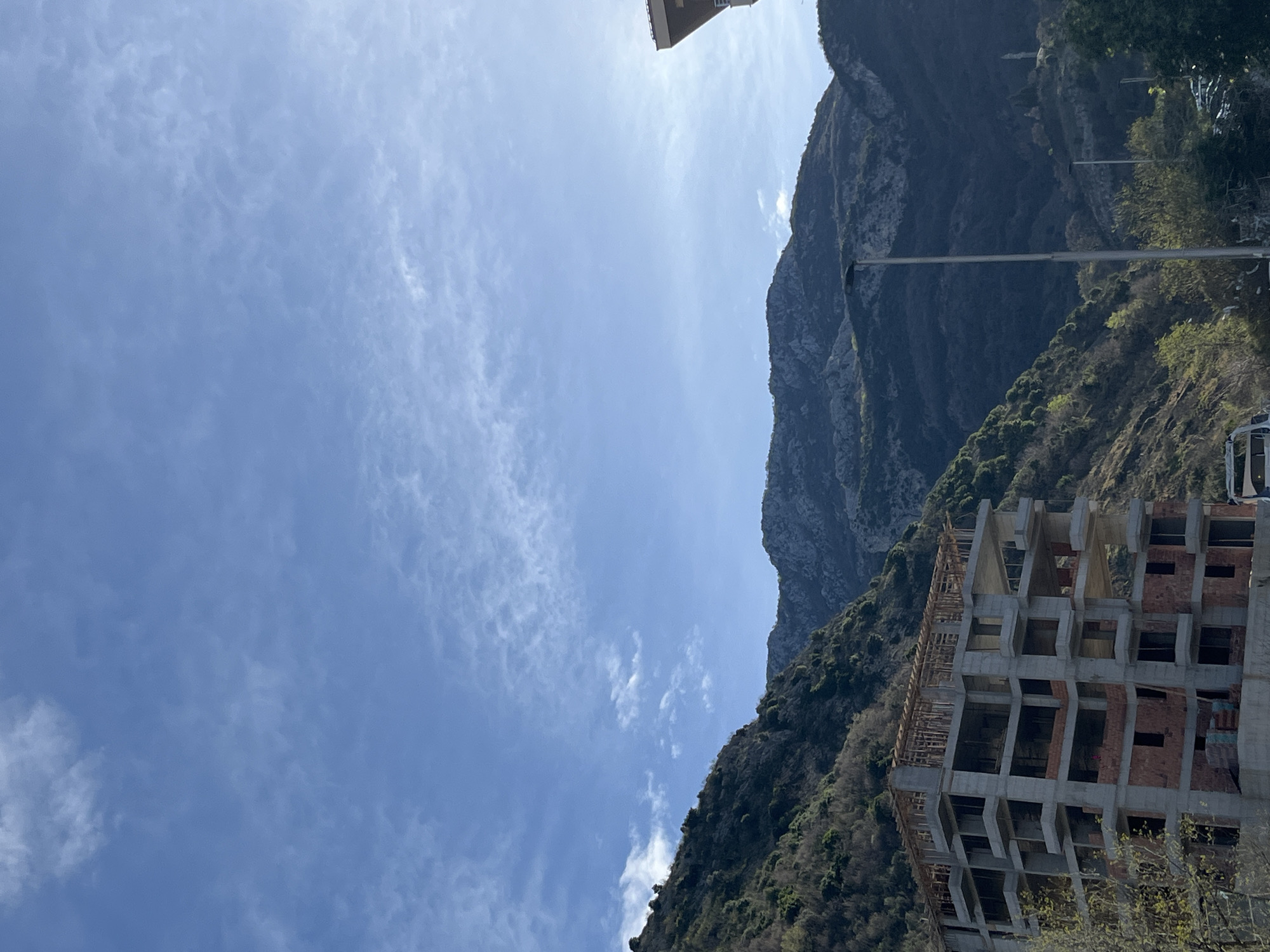 Woman holds real estate sign near Montenegro coastal buildings
