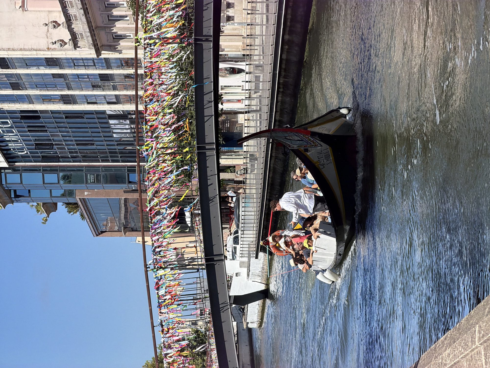 Tourist boat tours Aveiro's ribbon-decorated canal bridges on sunny morning