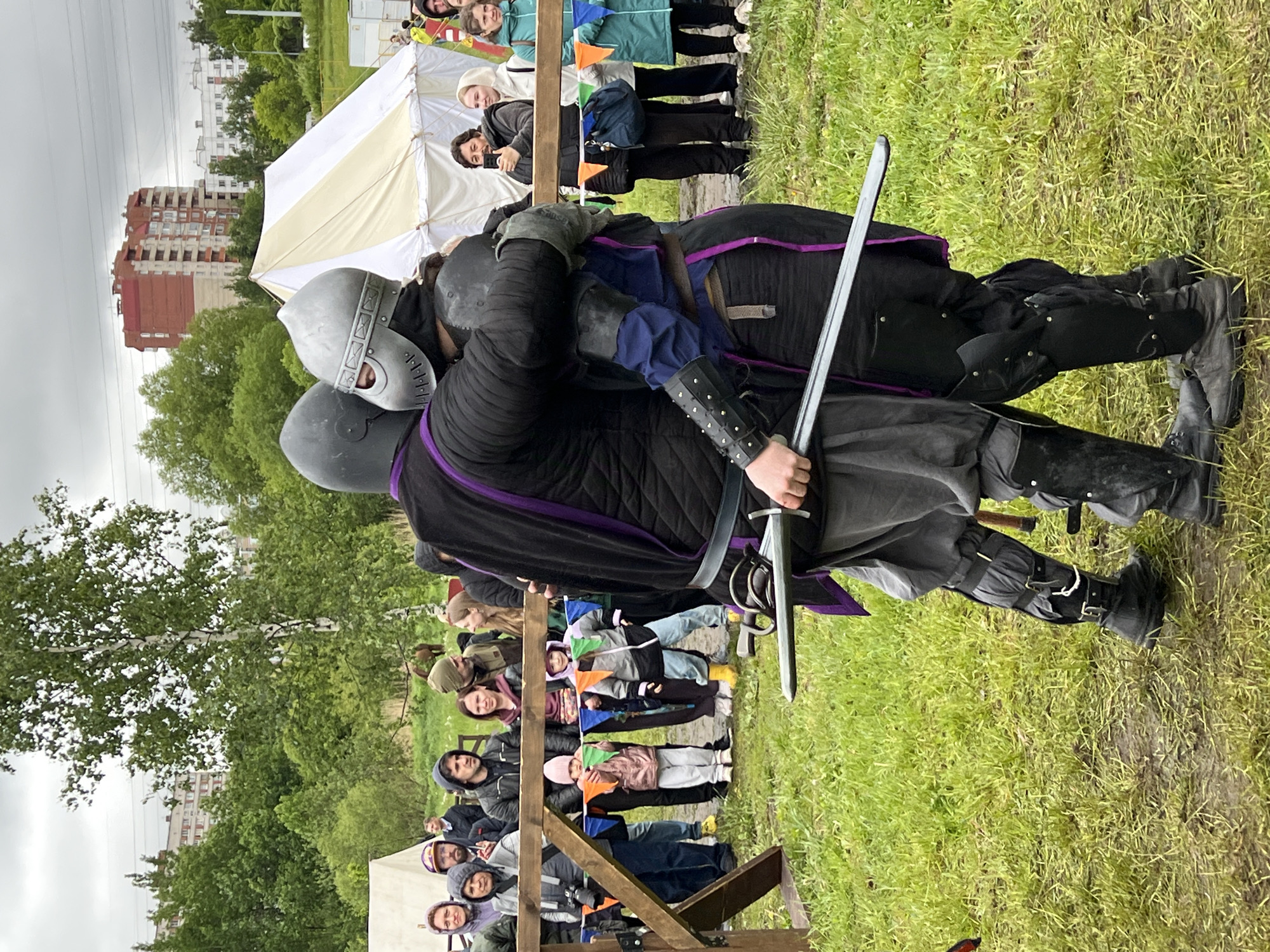 Medieval reenactment gathering features armored combat in field