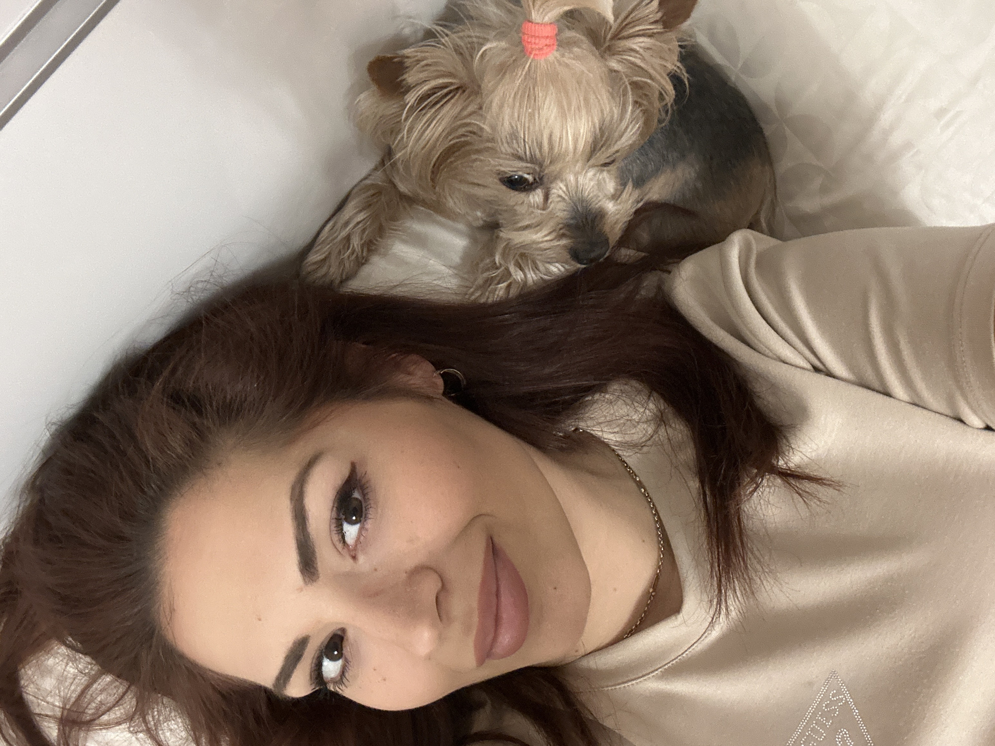 Woman and Yorkshire Terrier rest together on bed in Sofia