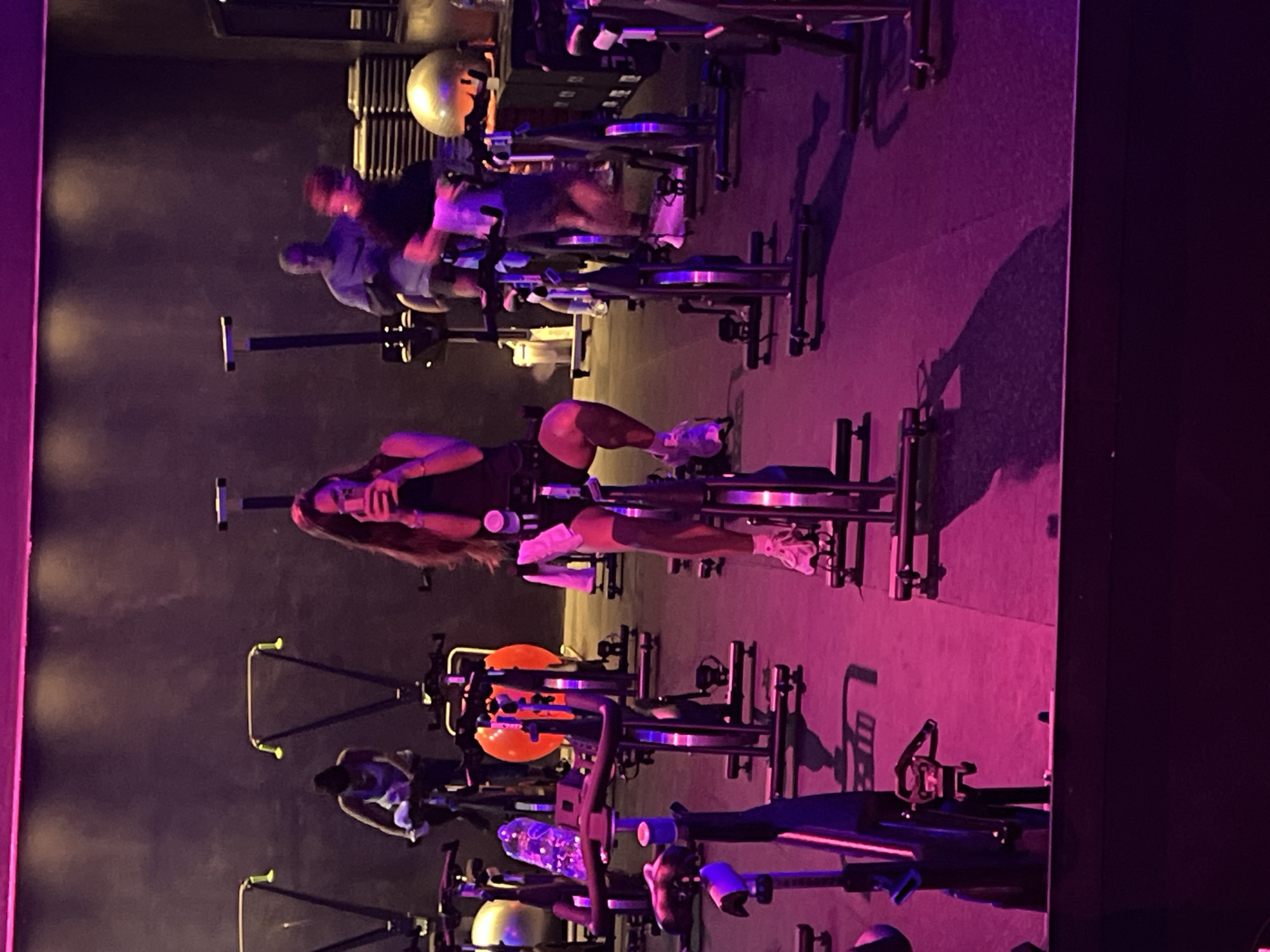 Early morning cycling class captured in purple-lit fitness studio