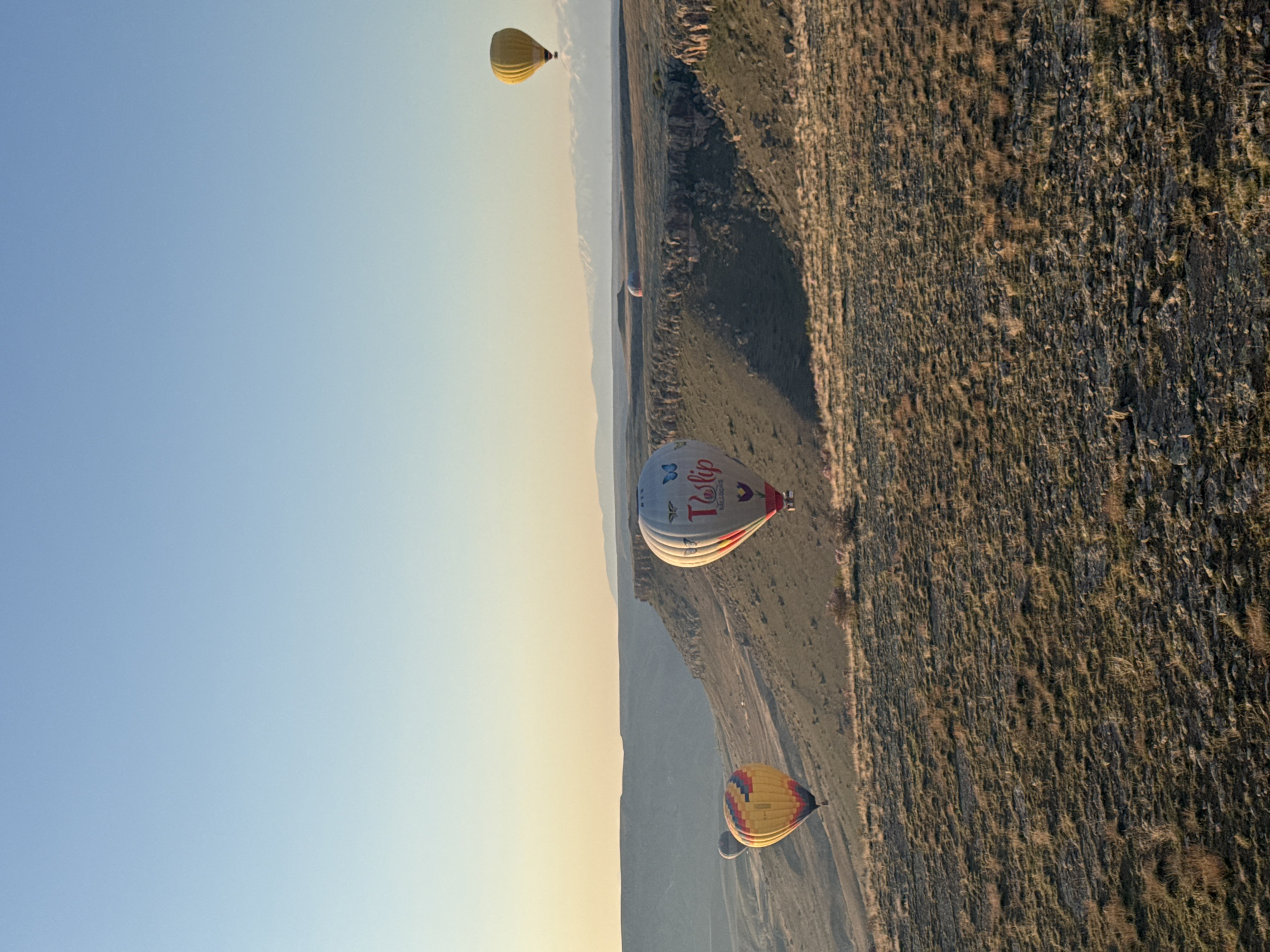 Hot air balloons drift over Turkish landscape at sunrise