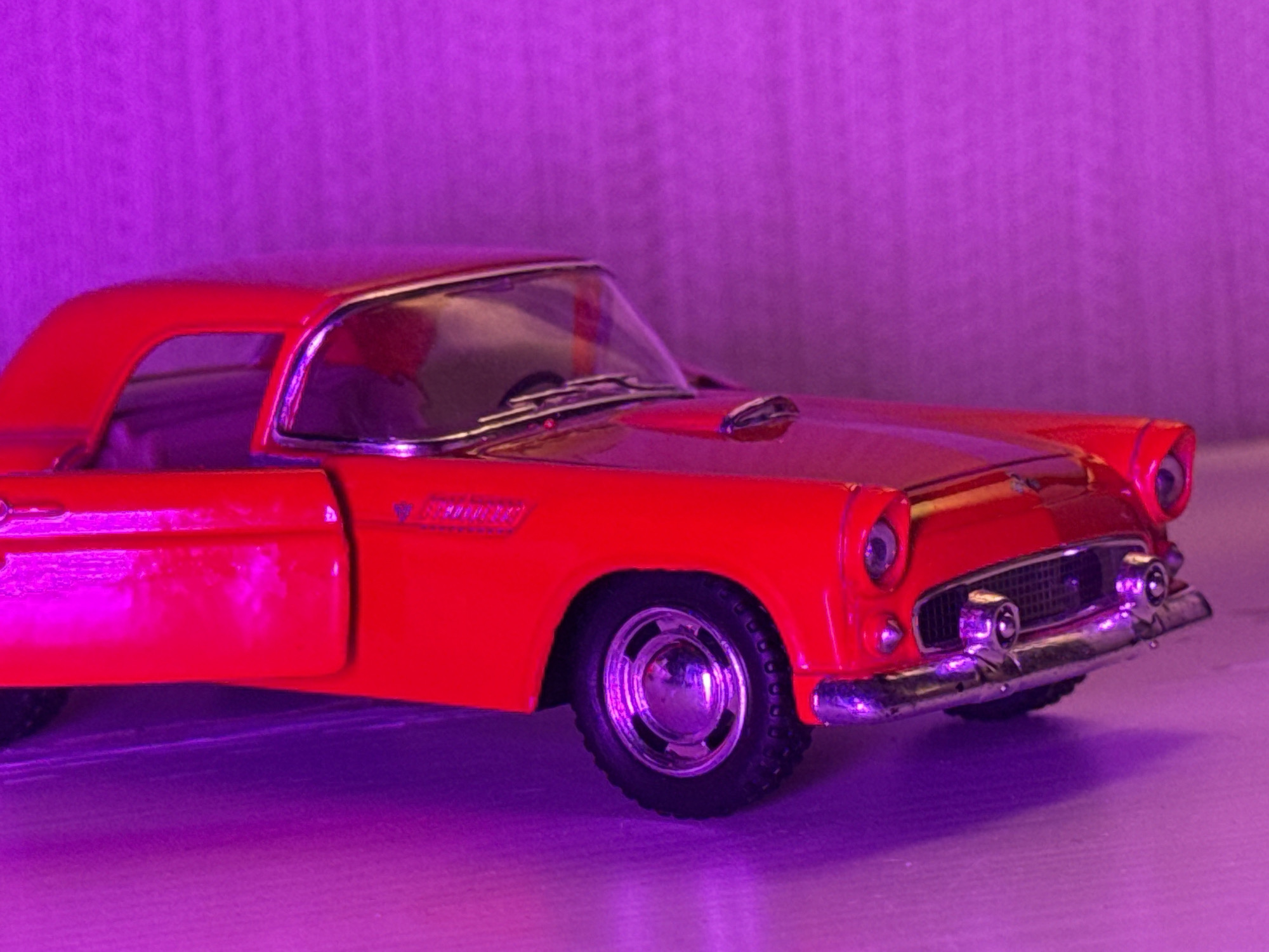 Red vintage toy car styled under moody purple light