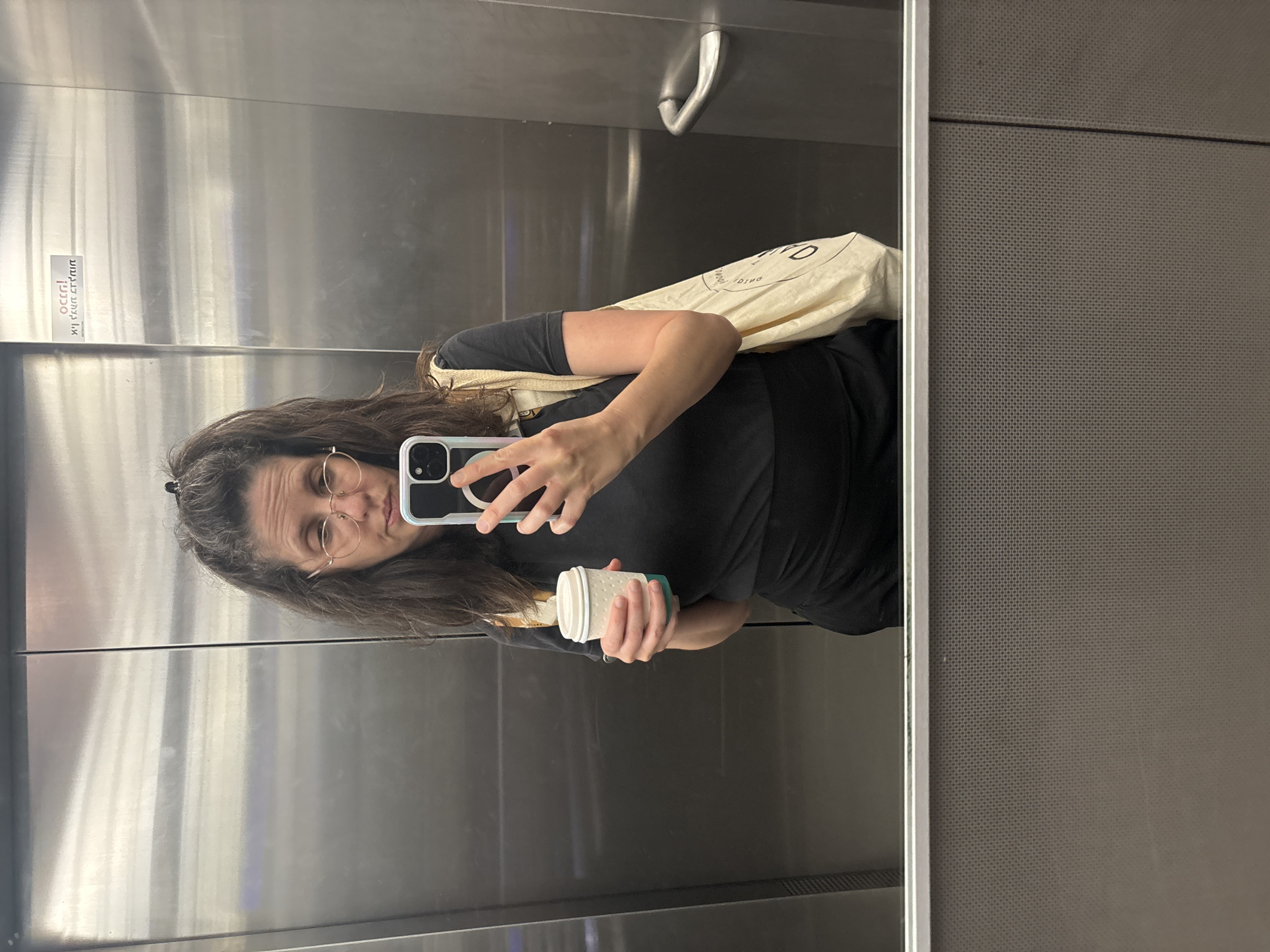Woman takes elevator selfie with coffee cup in Tel Aviv