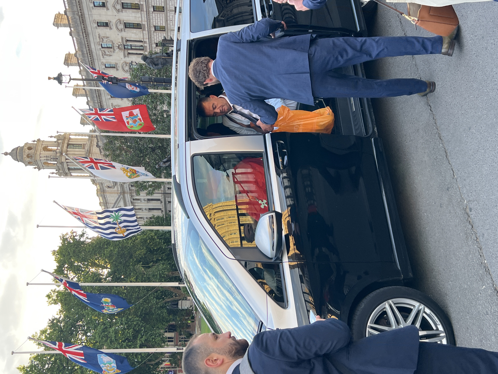 Suited man exits minivan with orange bag in London