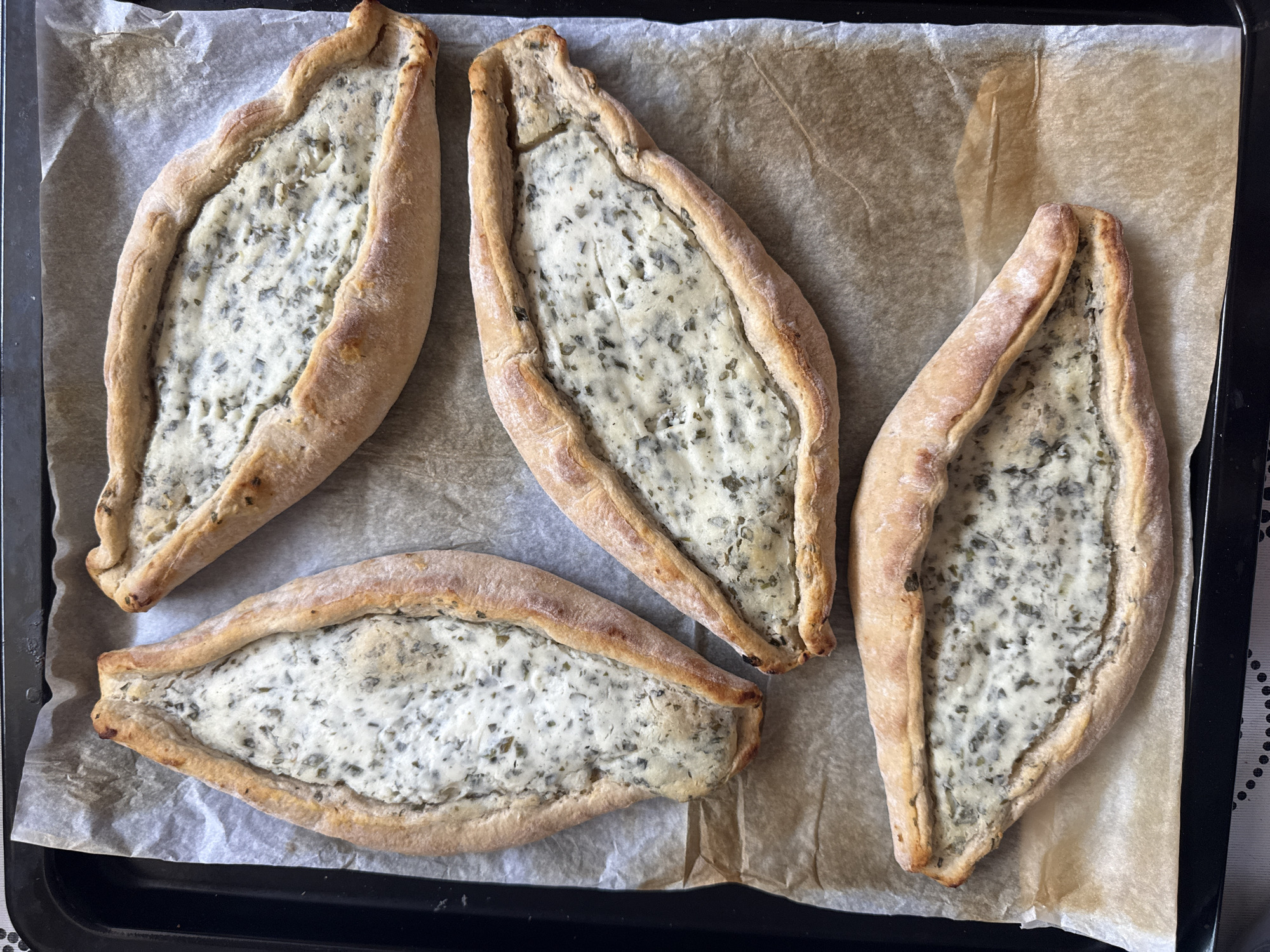 Four herb-filled boat pastries documented on baking sheet