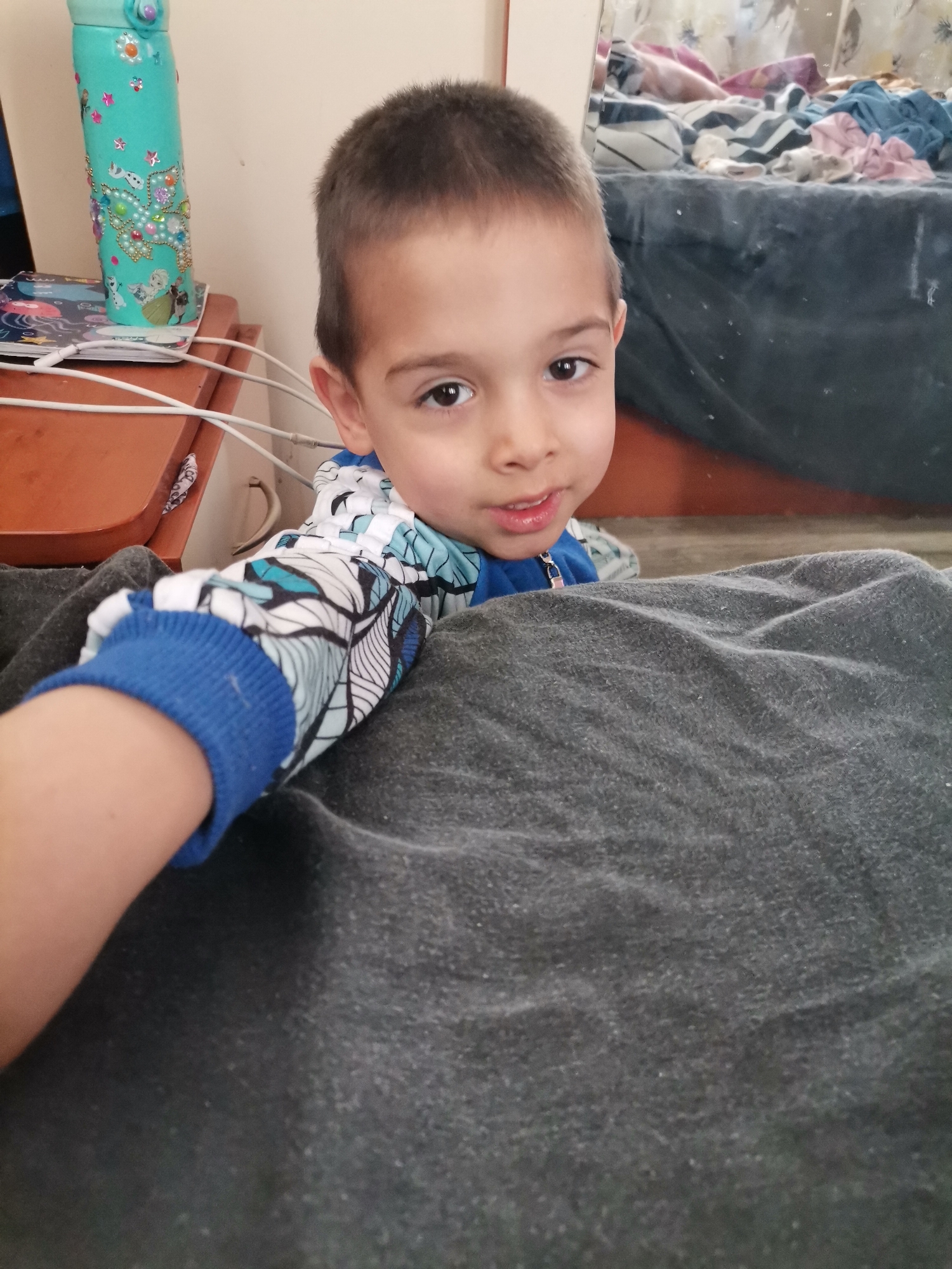 Child in blue patterned shirt captured resting, looking at camera