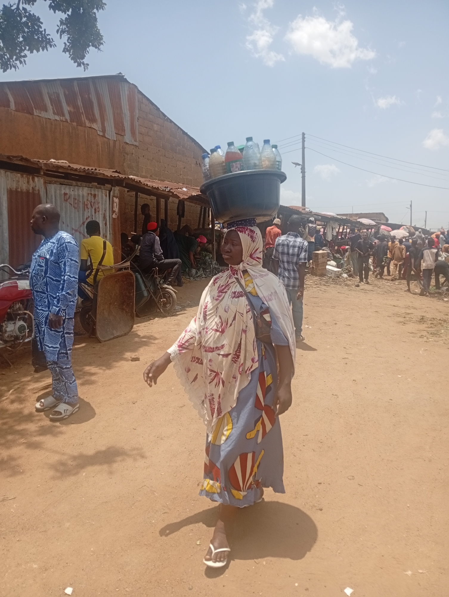 Market vendors carry water, flour through crowded outdoor marketplace