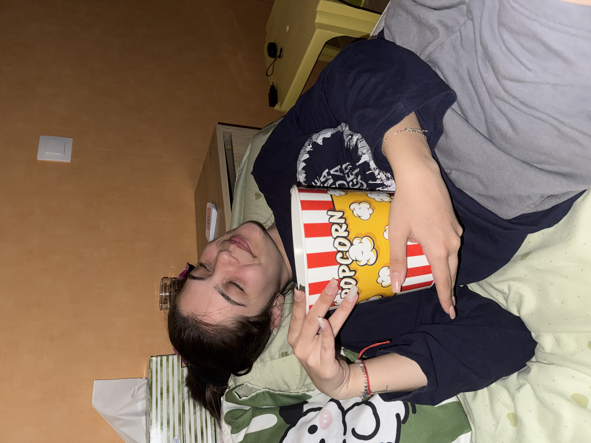 Woman enjoys popcorn while relaxing on bed in Sliven