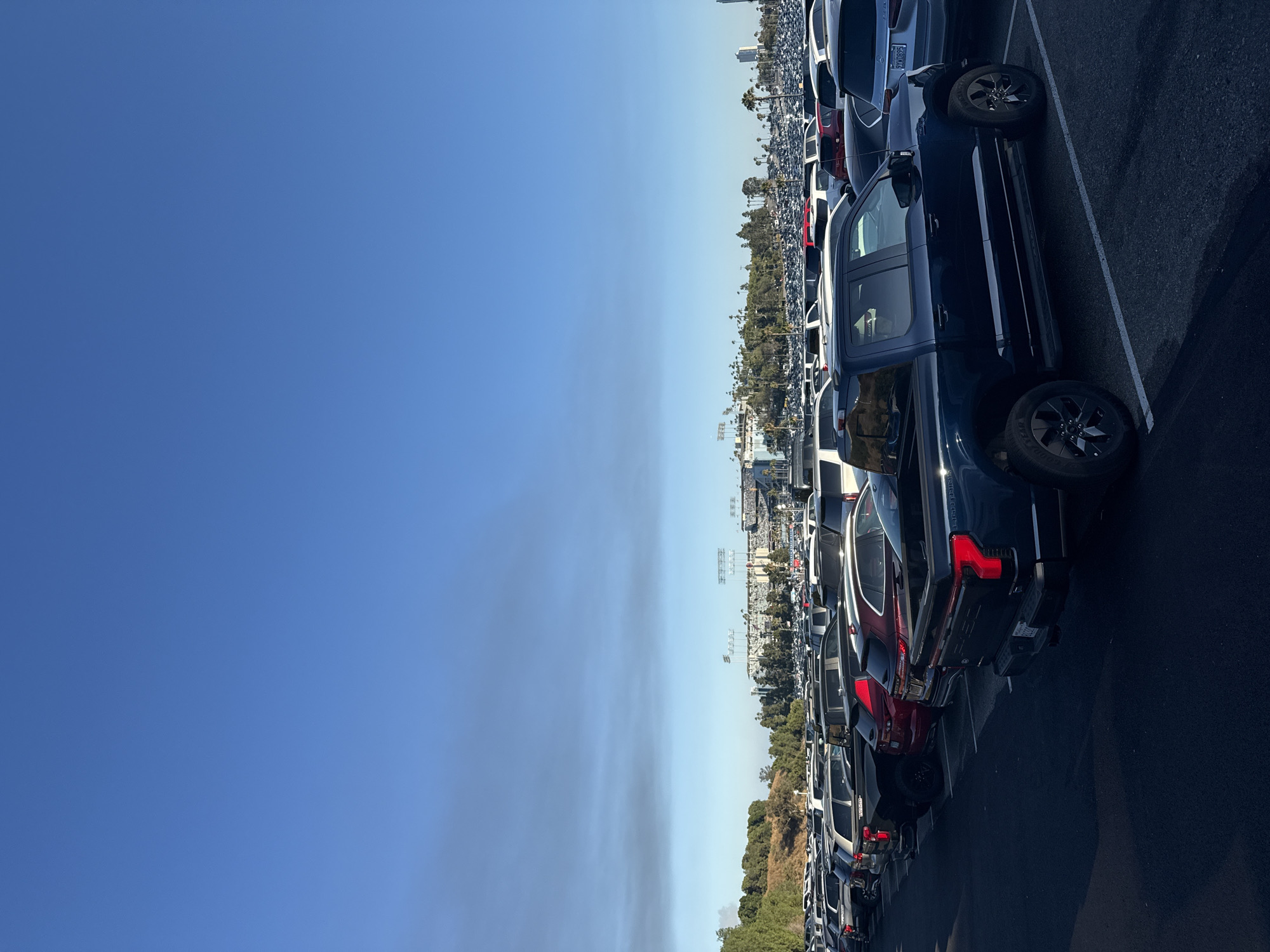 Packed stadium parking lot stretches toward the venue under blue skies