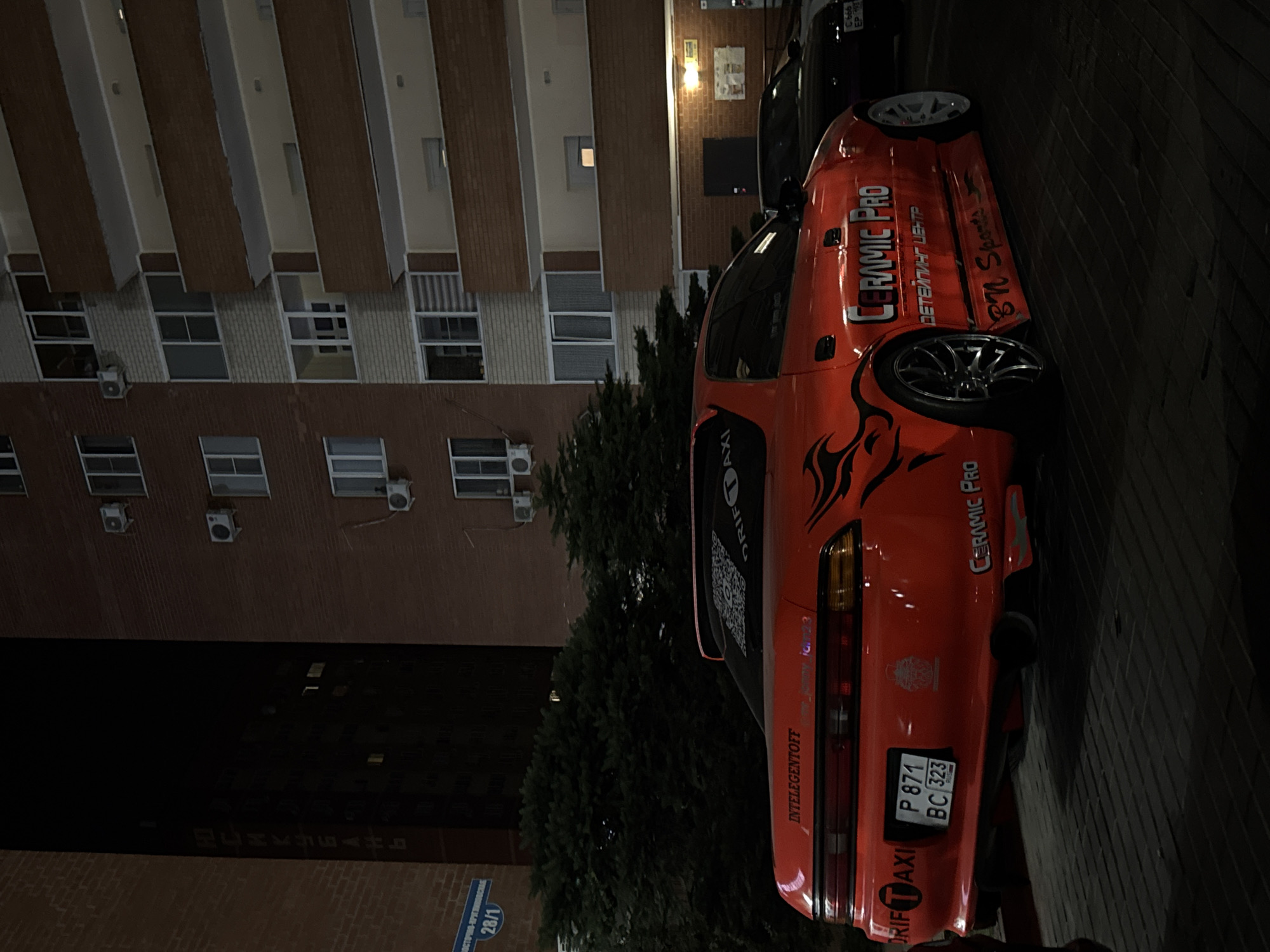 Modified drift car and neon signage on a brick-paved night street