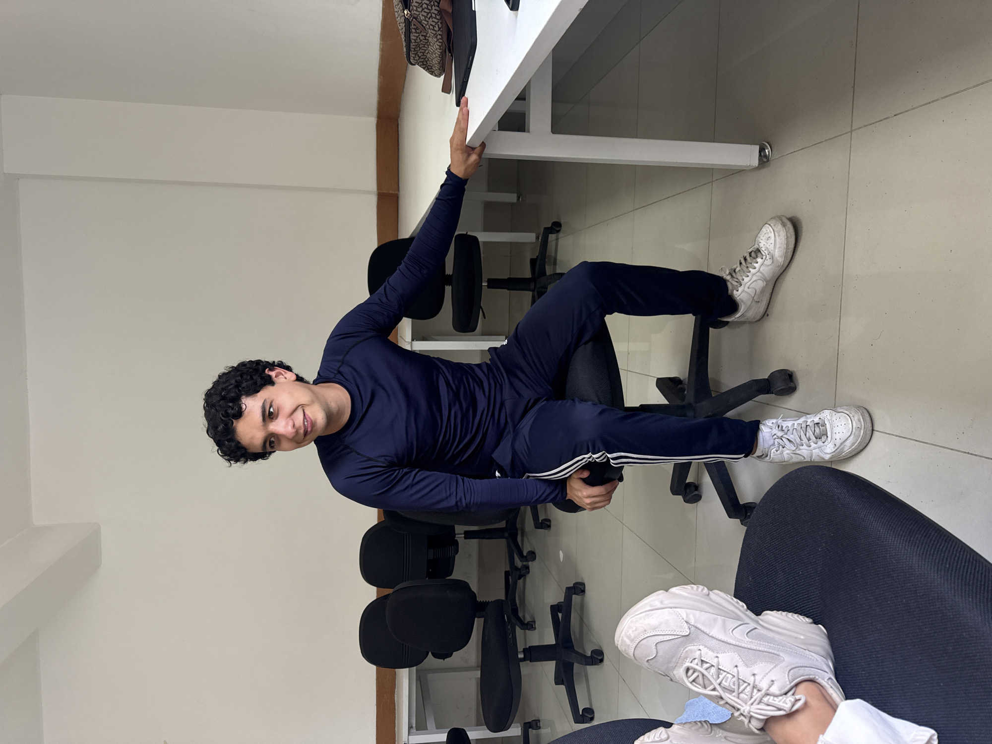 Man in tracksuit sits in office chair, San Andrés Cholula