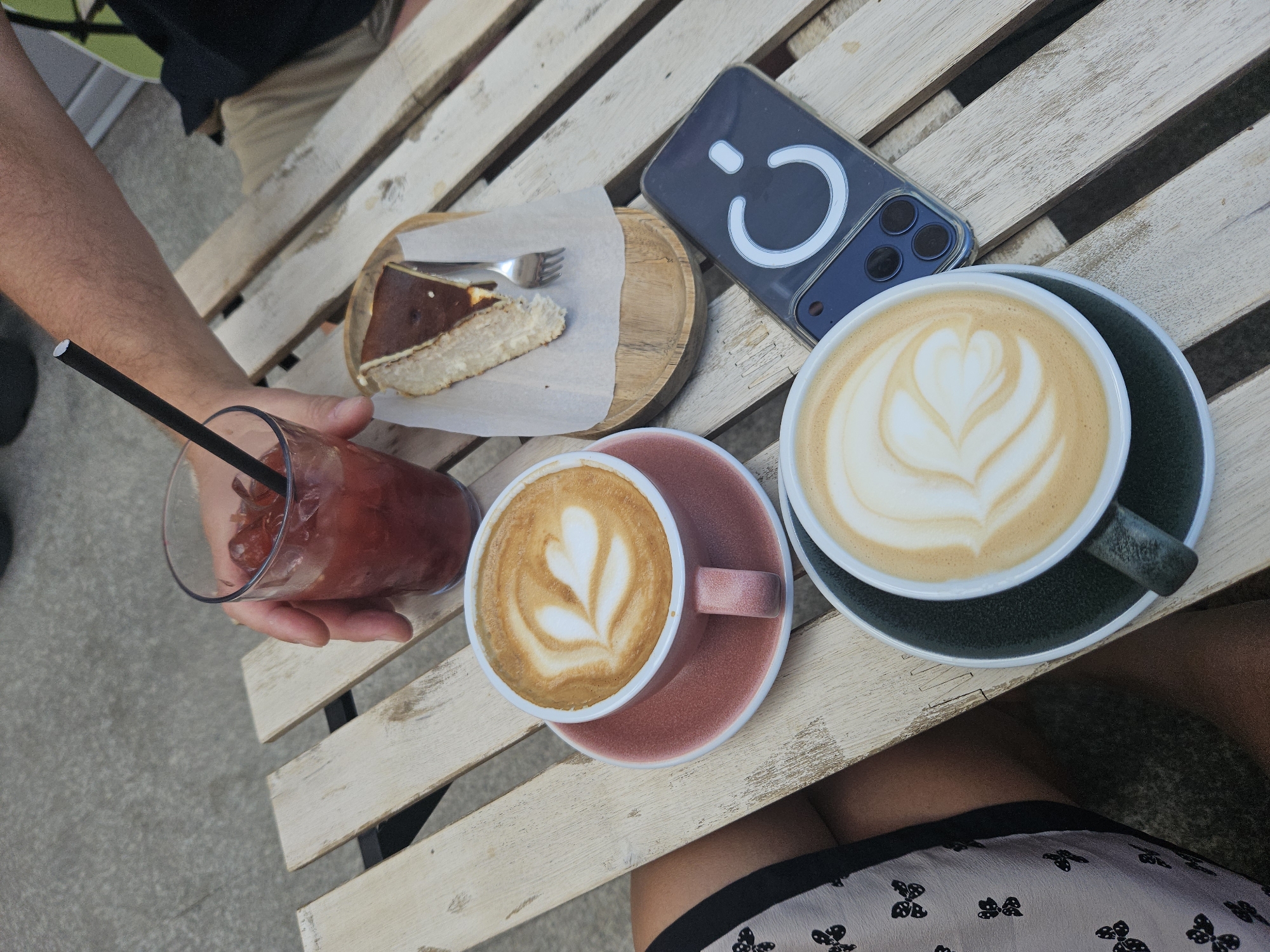 Café table with lattes, cheesecake, and iced drink, multiple angles