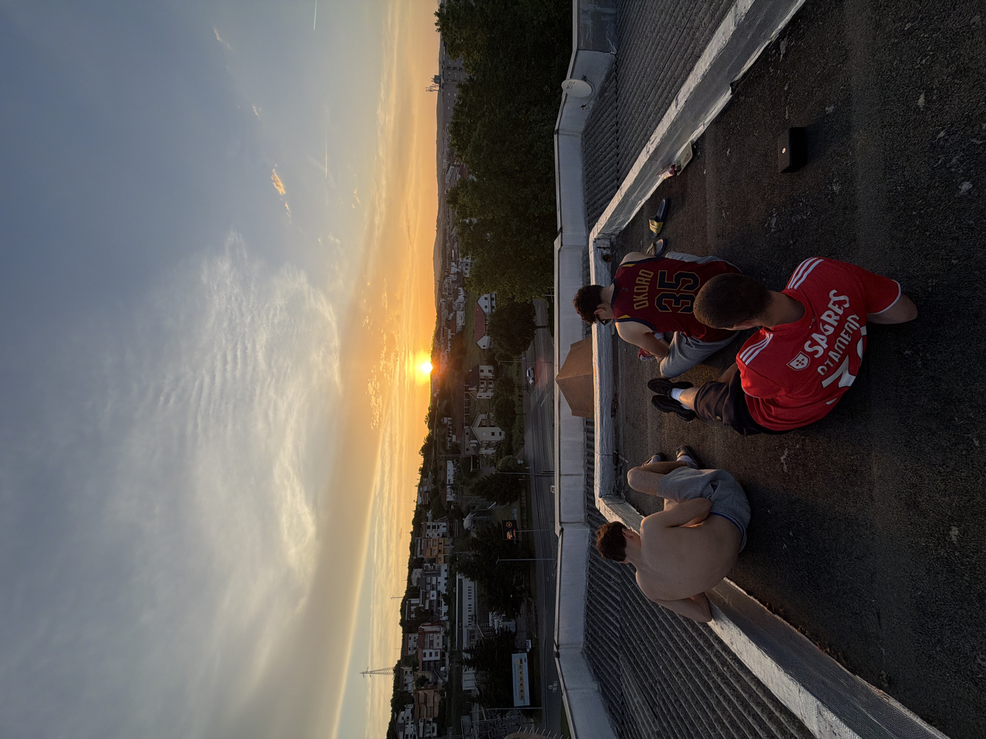 Young men watch sunset from Bragança rooftop