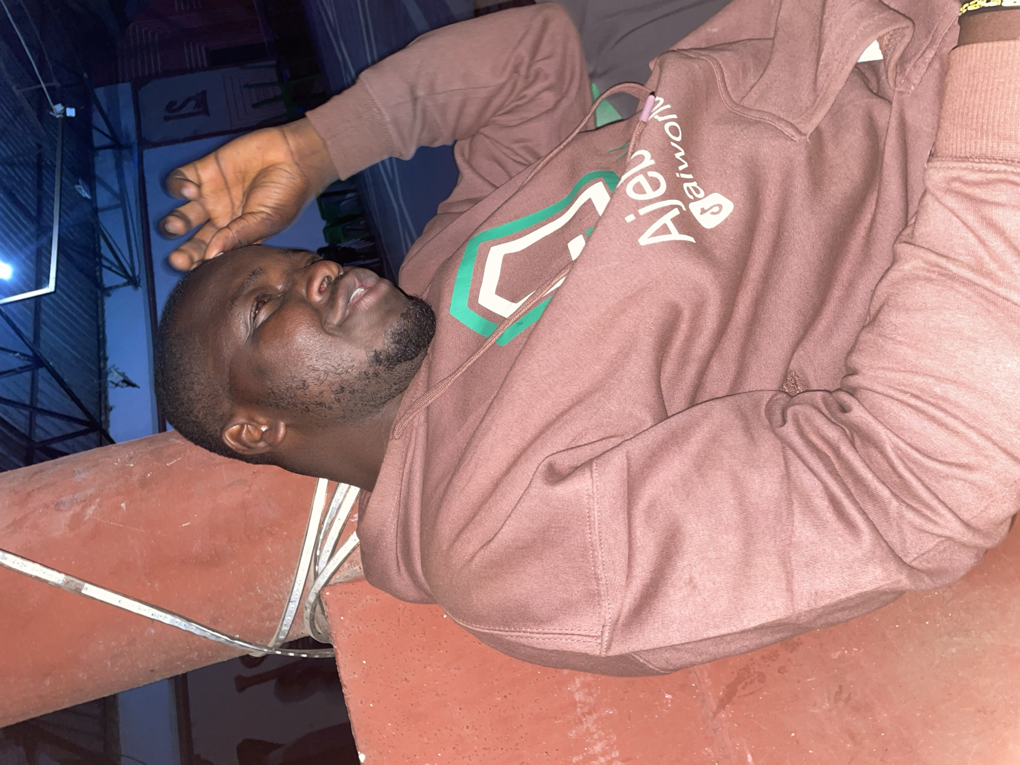 Man in brown hoodie lies on red tiles in Jos