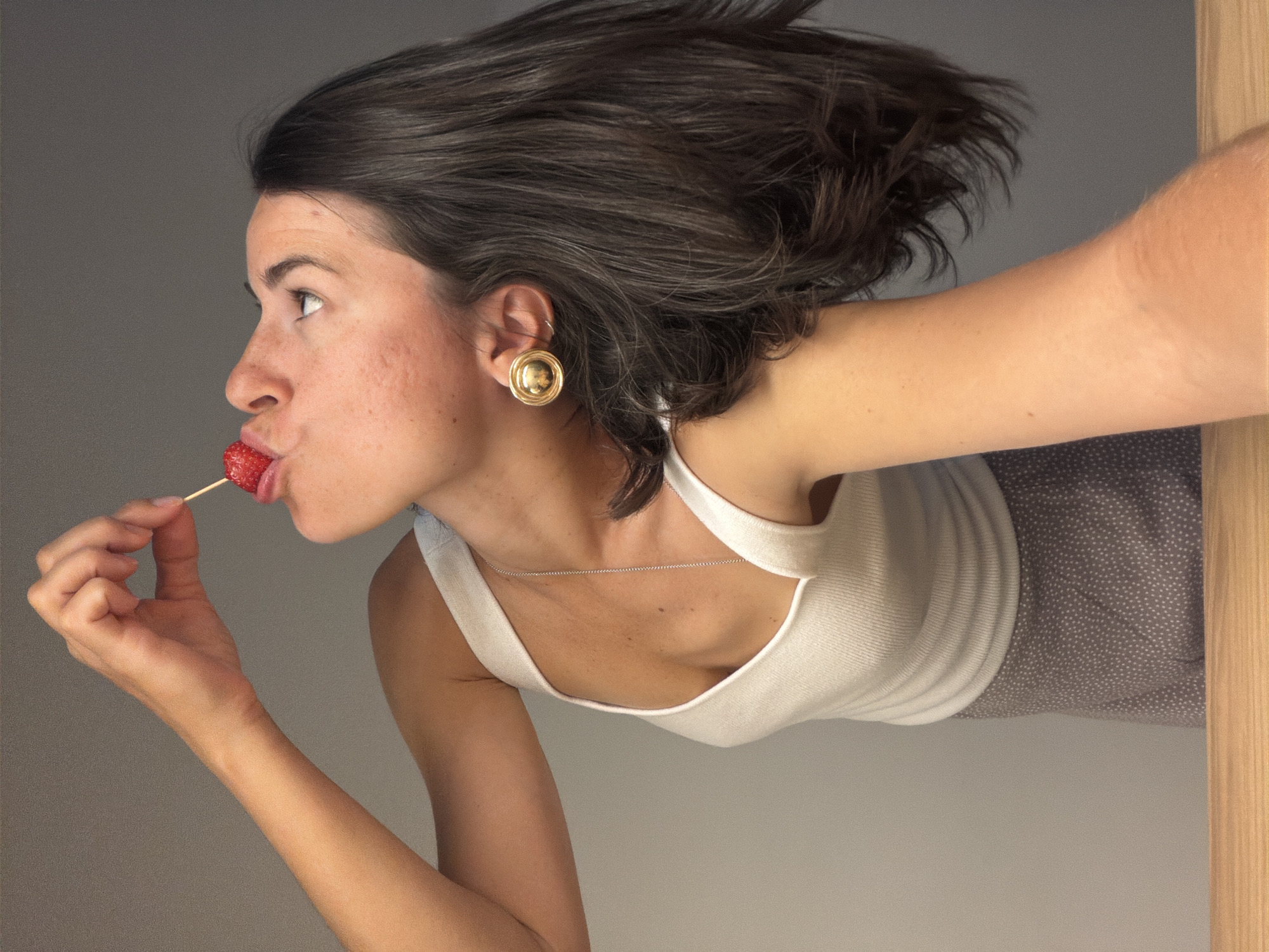 Woman poses playfully with strawberries and Buddha statue in Montenegro