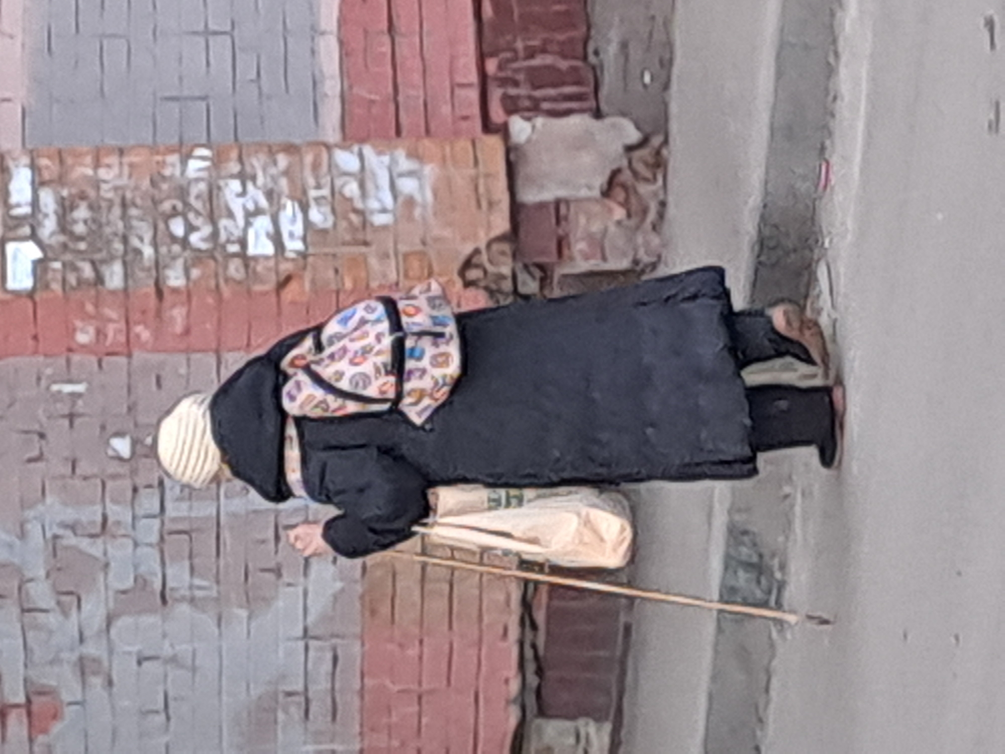 Woman walks with walking stick on Elektrostal sidewalk