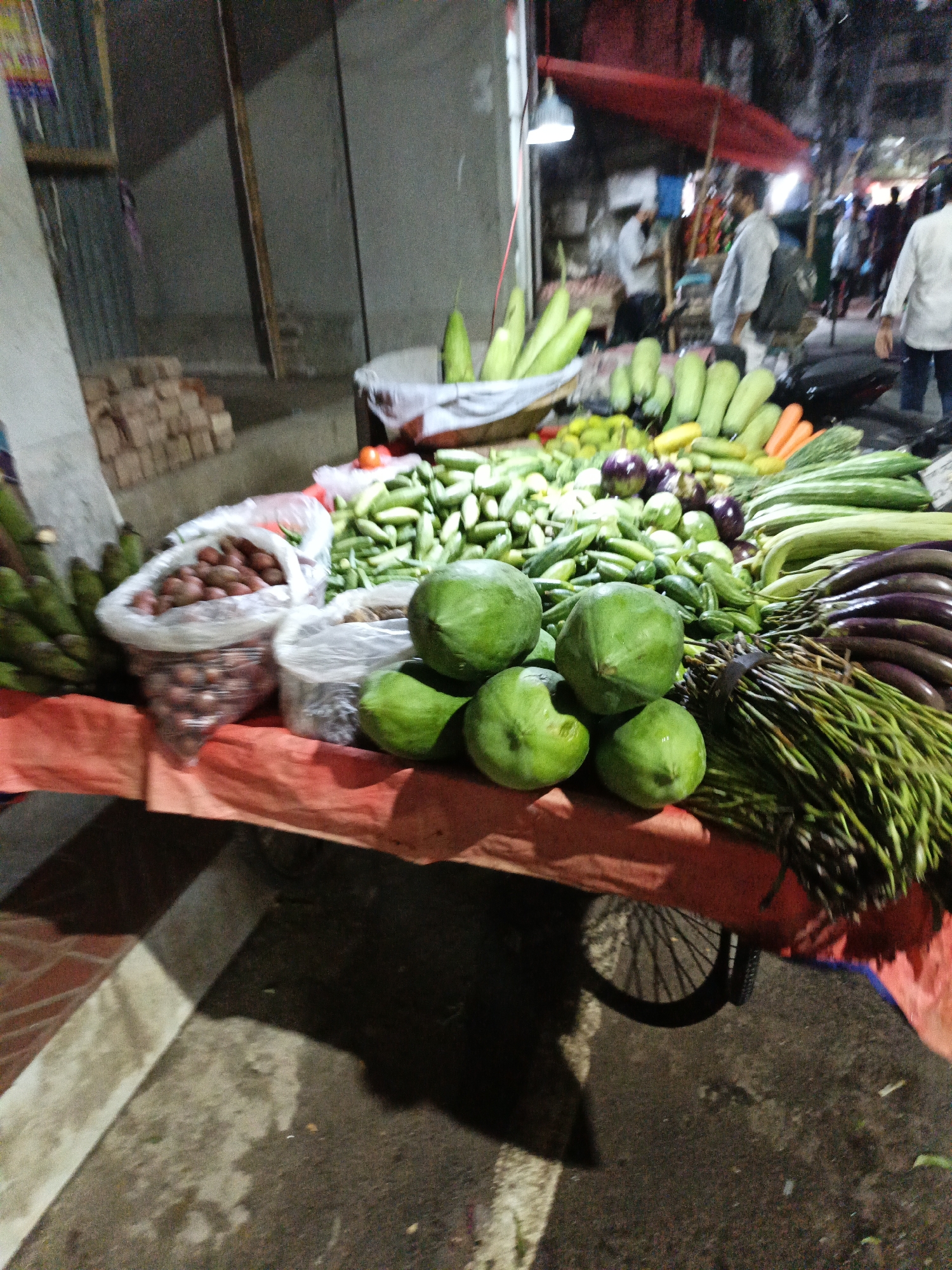 Street vegetable cart runs under artificial lights in Dhaka