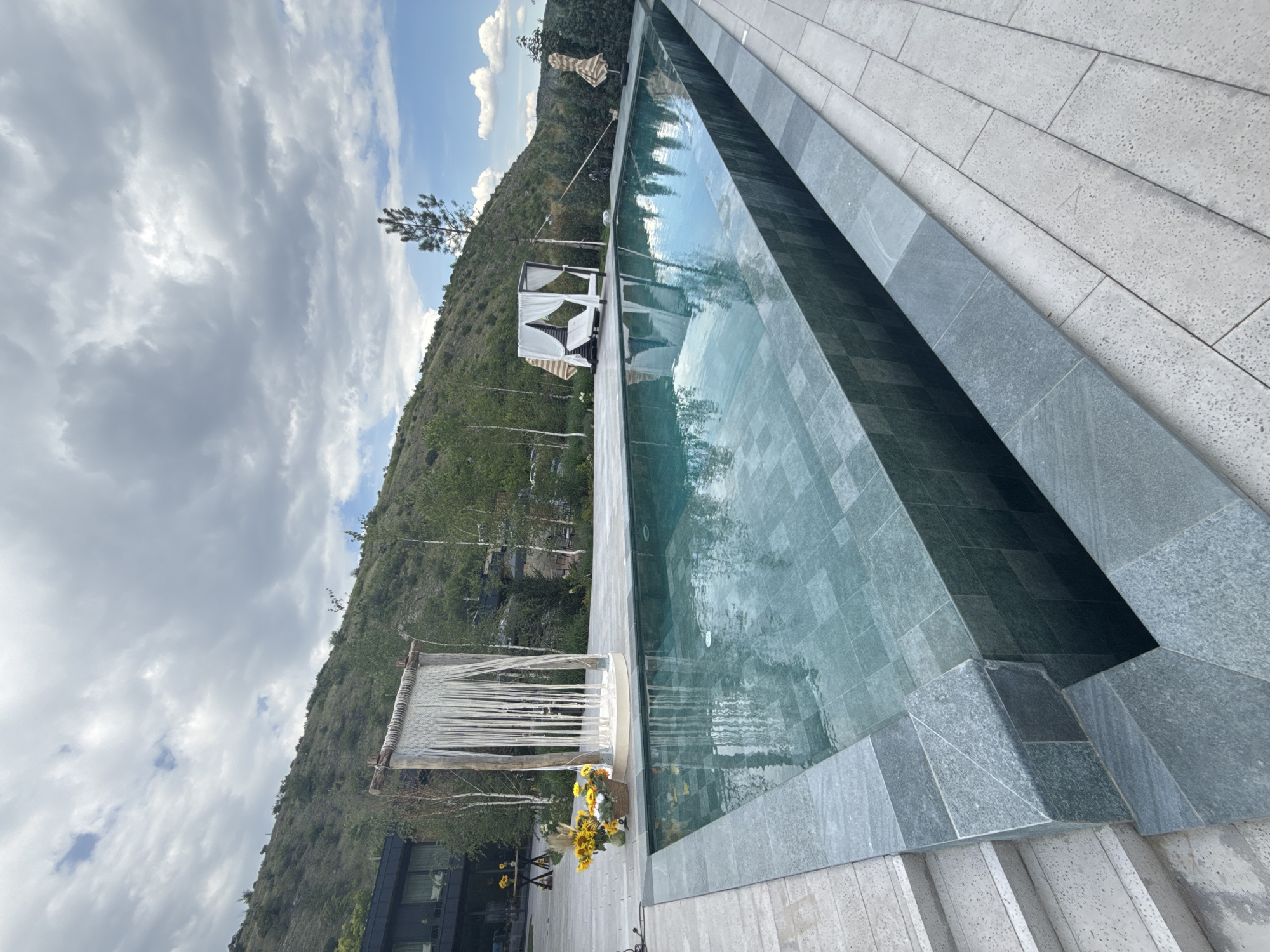 Outdoor event setup with florals, pool, and sports cars in Morovaia
