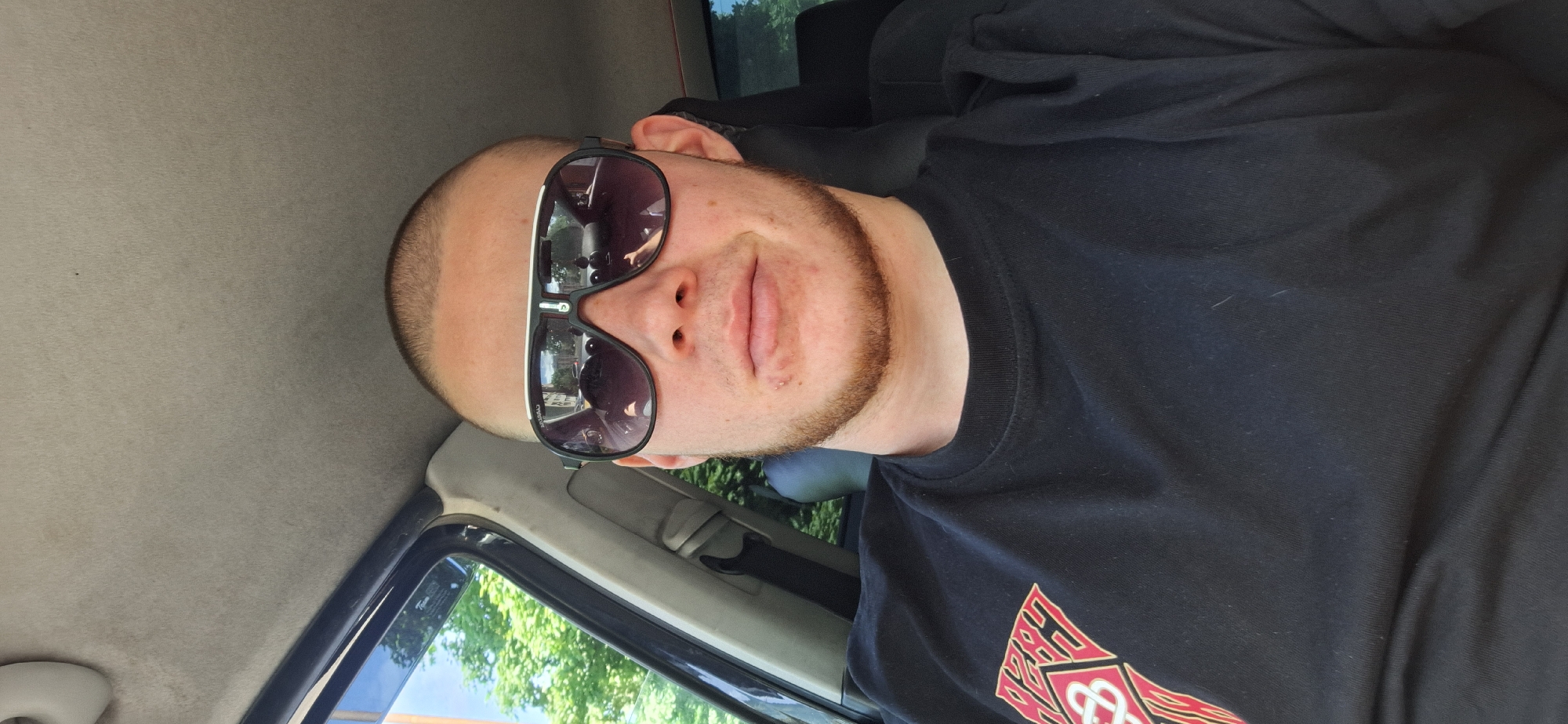 Man in sunglasses sits in vehicle near greenery in Burgas