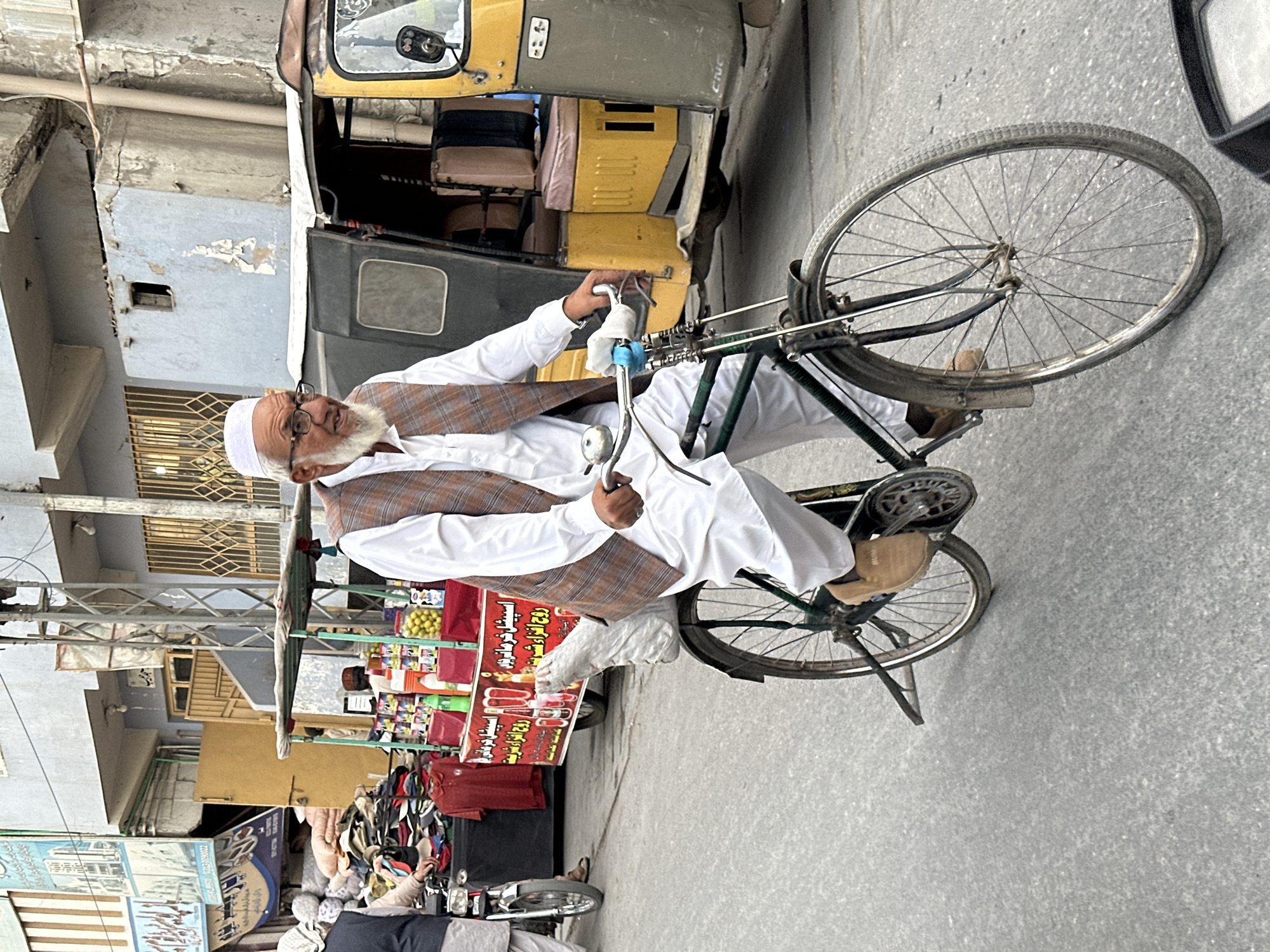 Elderly man cycles through Quetta streets in traditional dress