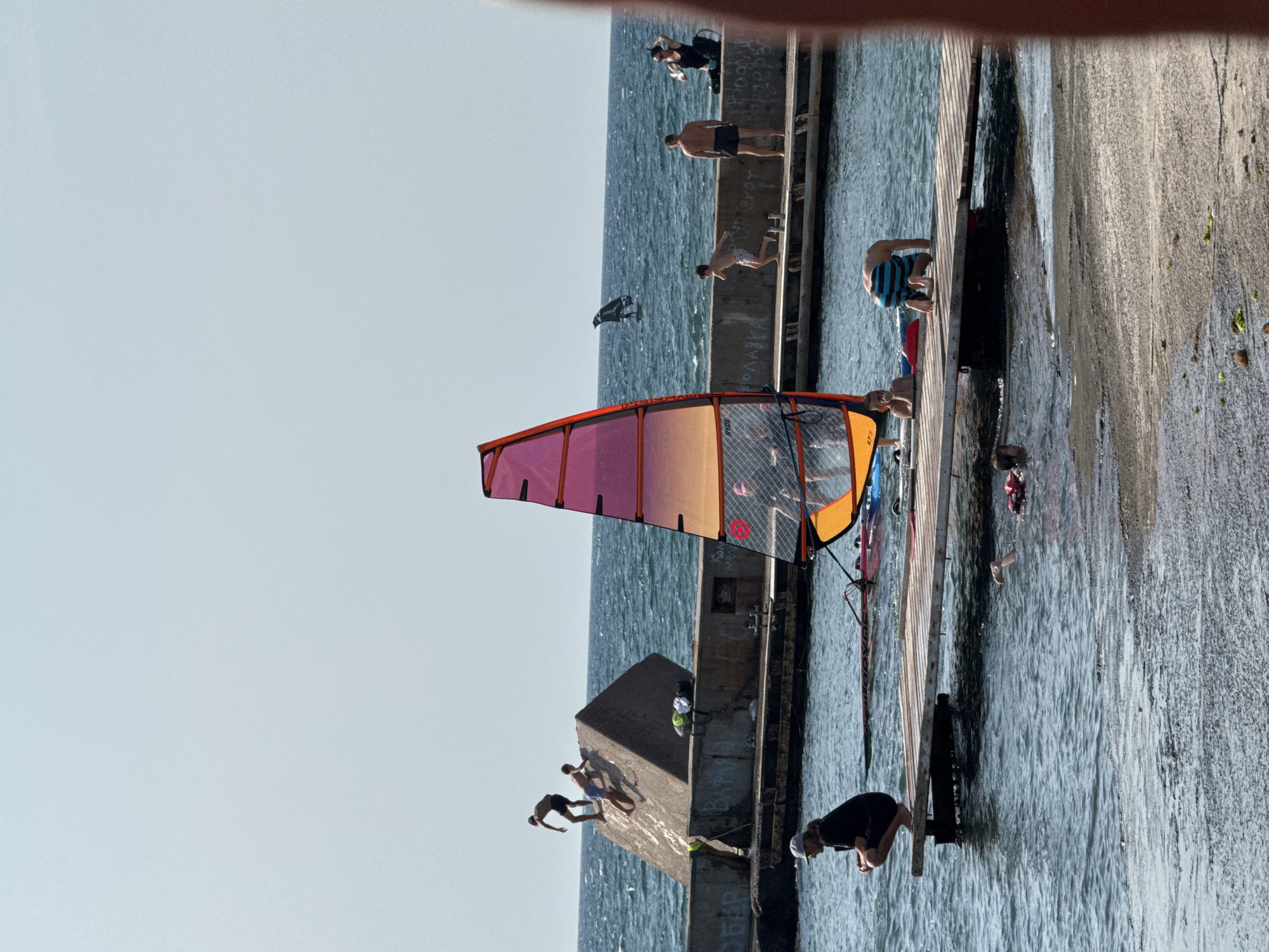 Windsurfing, kiteboarding, and kayaking at a sunny waterfront
