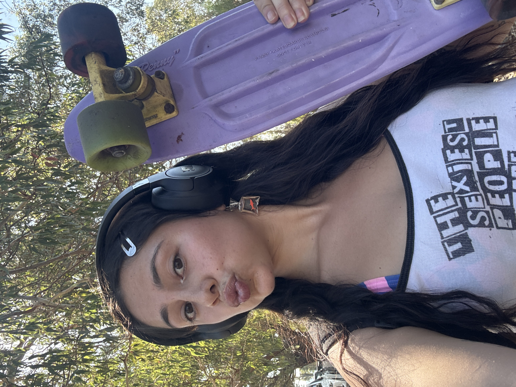 Woman holds purple skateboard overhead in South Perth