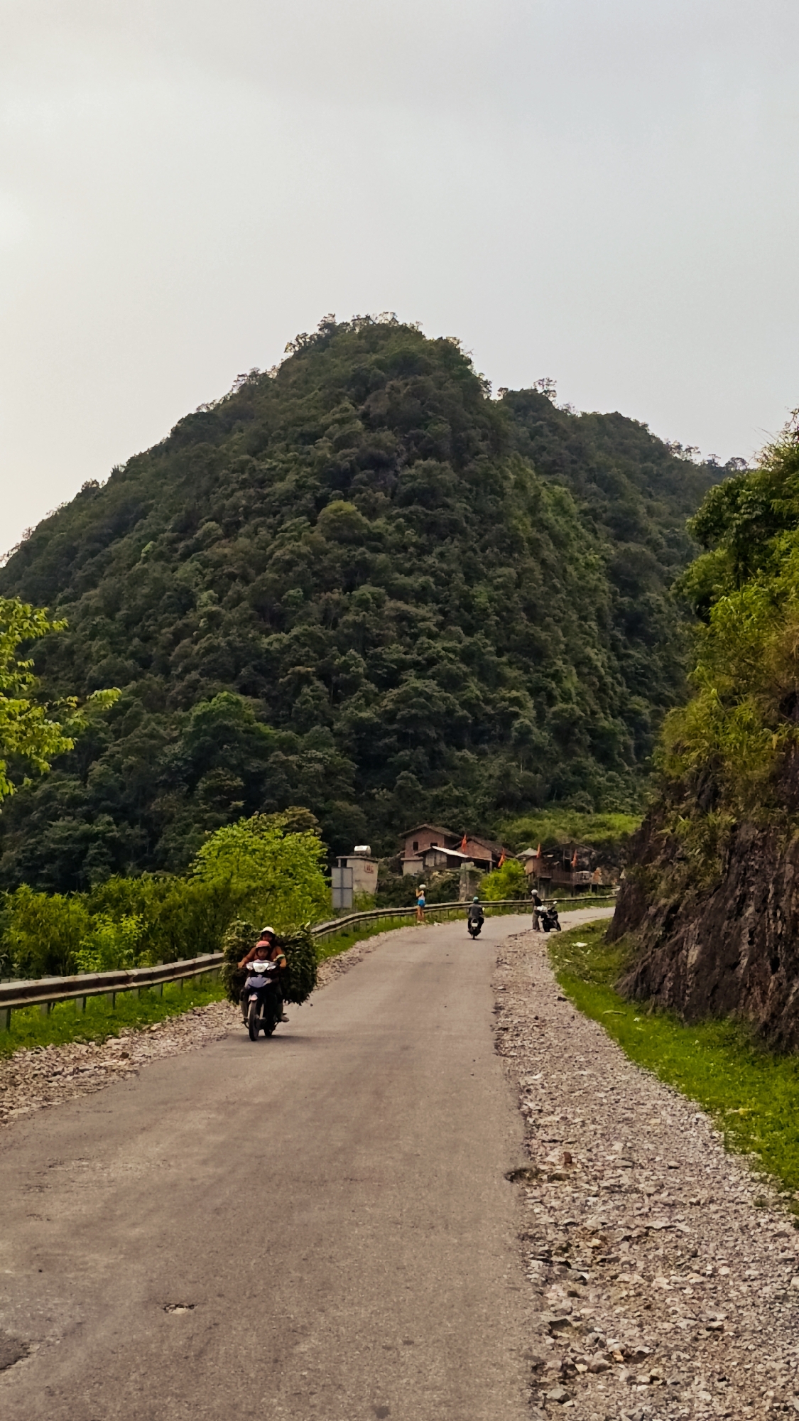 Motorcyclist travels mountain road in rural Vietnam commune