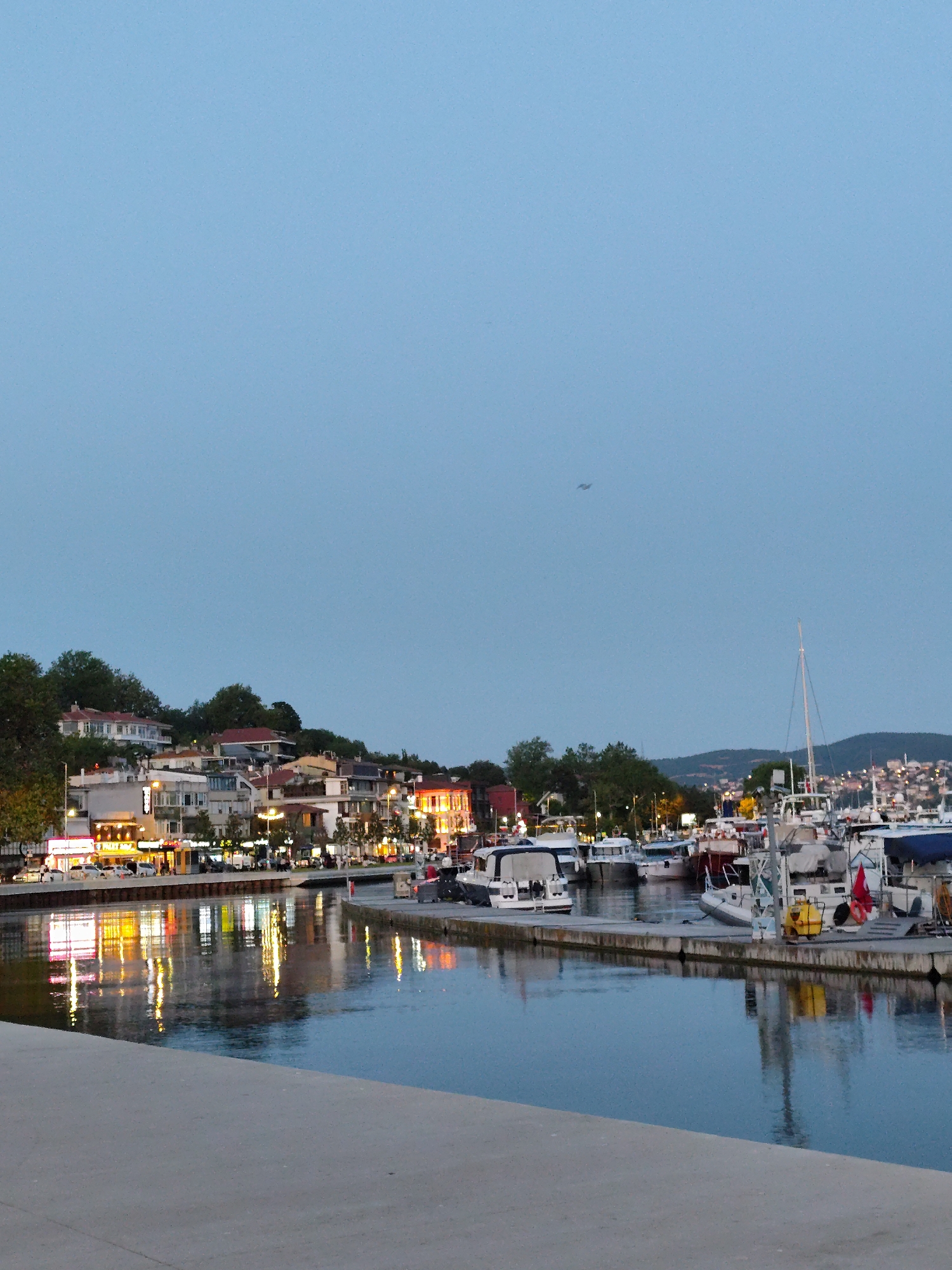 Sarıyer harbor at dusk, boats docked along a calm waterfront