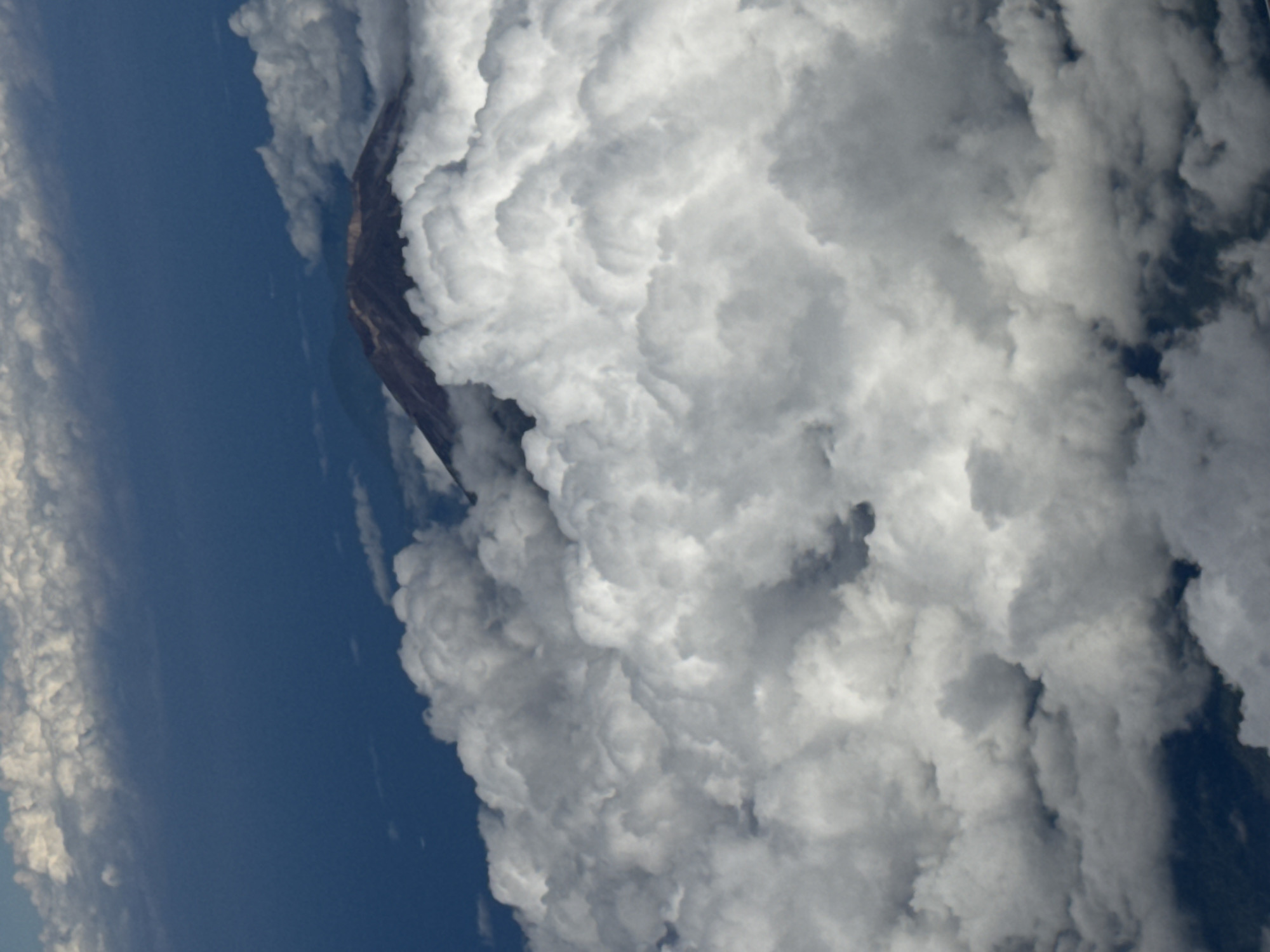 Aircraft passenger witnesses clouded mountain peaks over Bangli, Indonesia