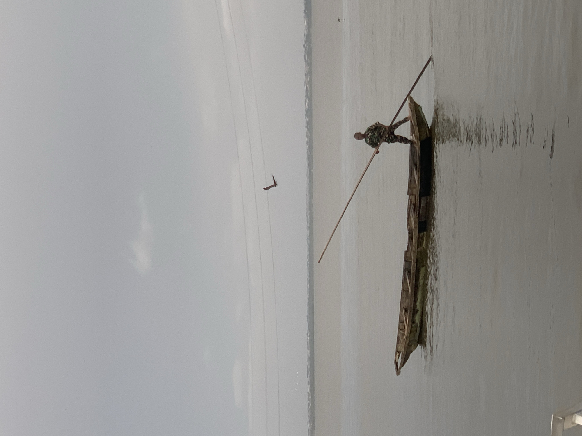 Man poles wooden boat in waters near Ikoyi, Nigeria