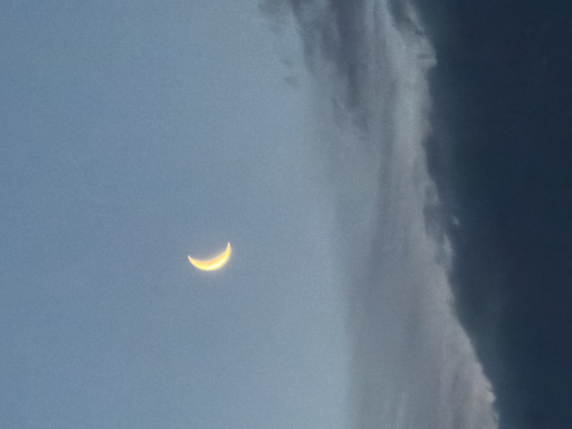 Crescent moon photographed through clouds in Luxembourg early morning