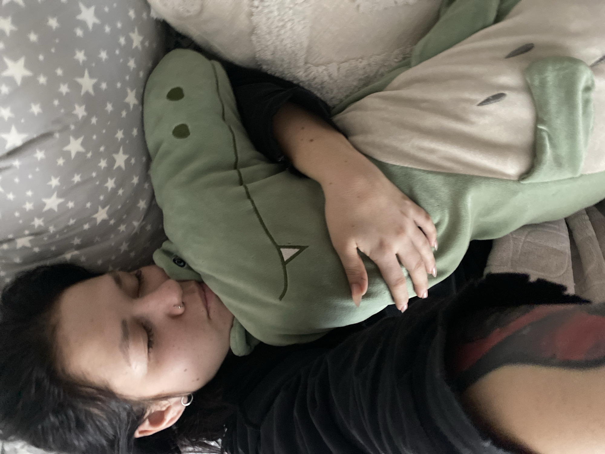 Person in dinosaur onesie rests in bed in Chaikovsky