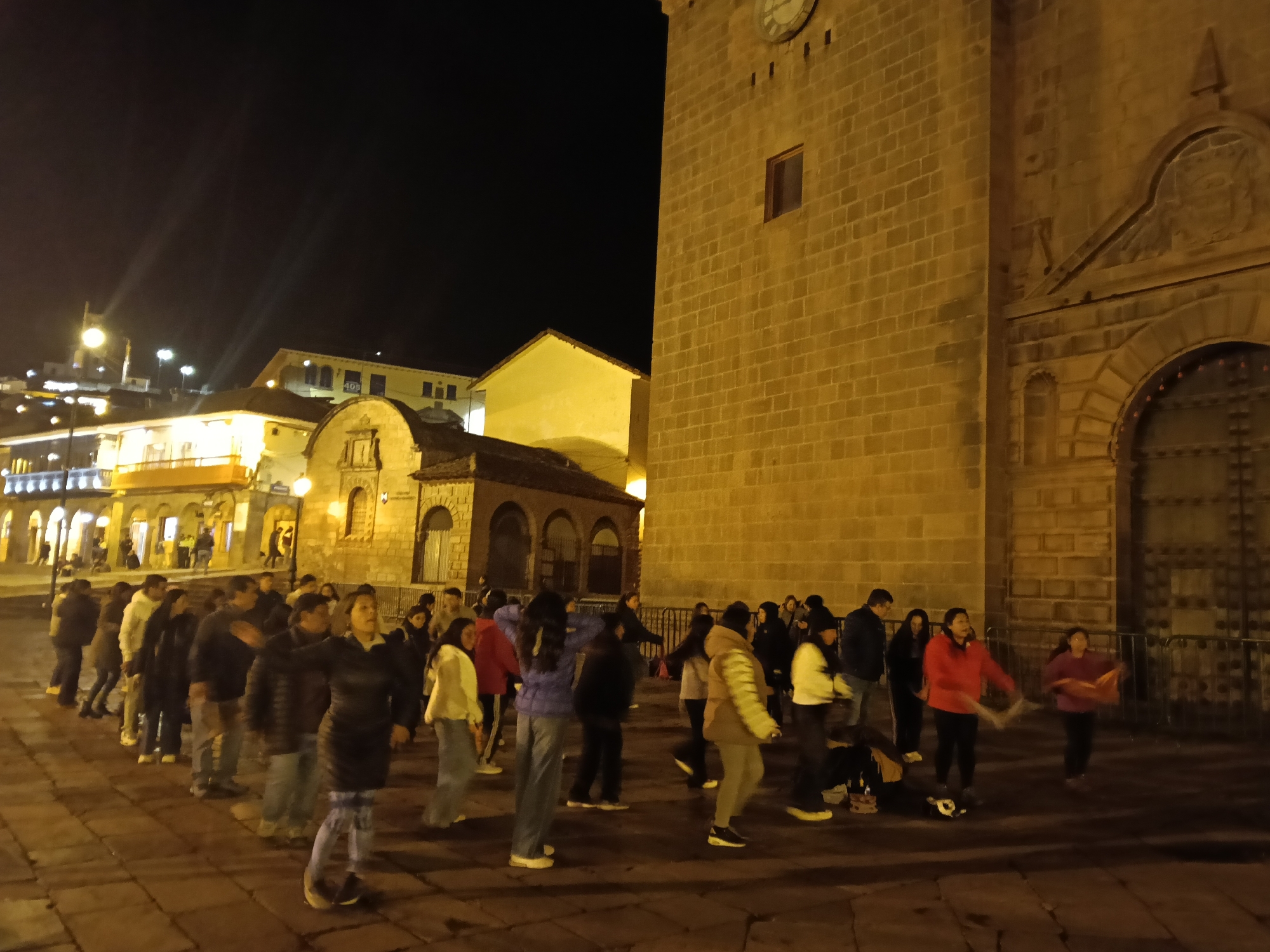 Nighttime gathering with dancing, white flags in Cusco plaza