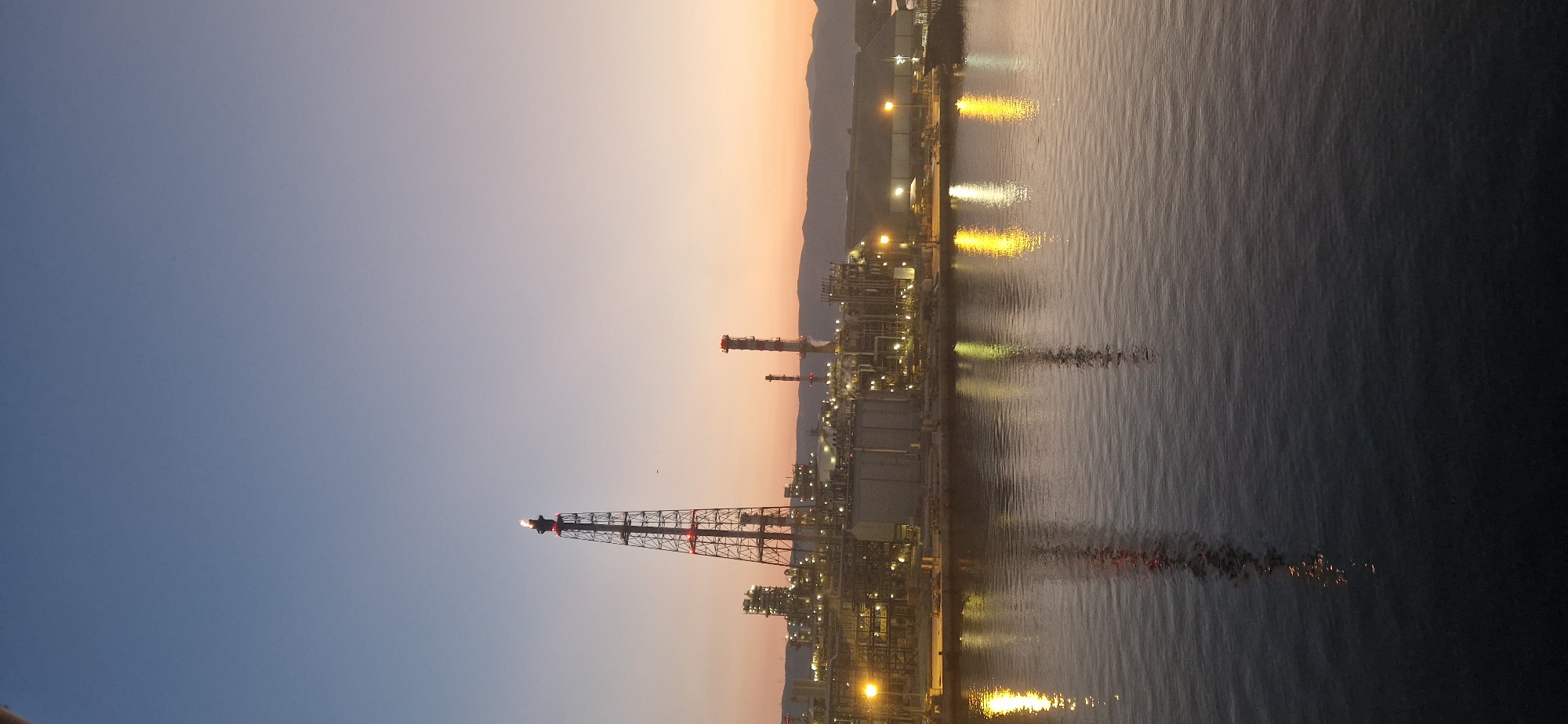 Industrial waterfront at dusk, sky painted in gradient hues