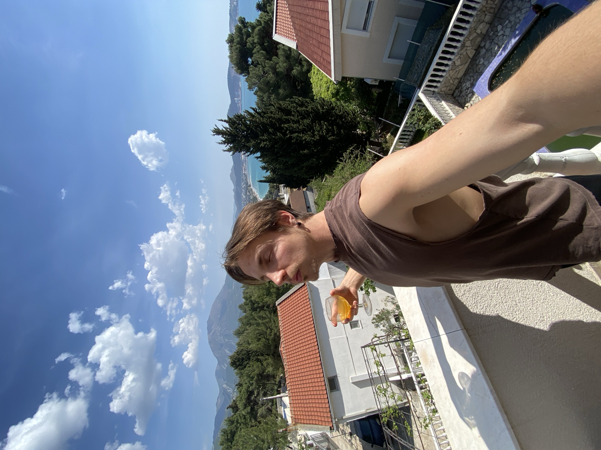Man enjoys drink on sunny balcony in Montenegro coastal town