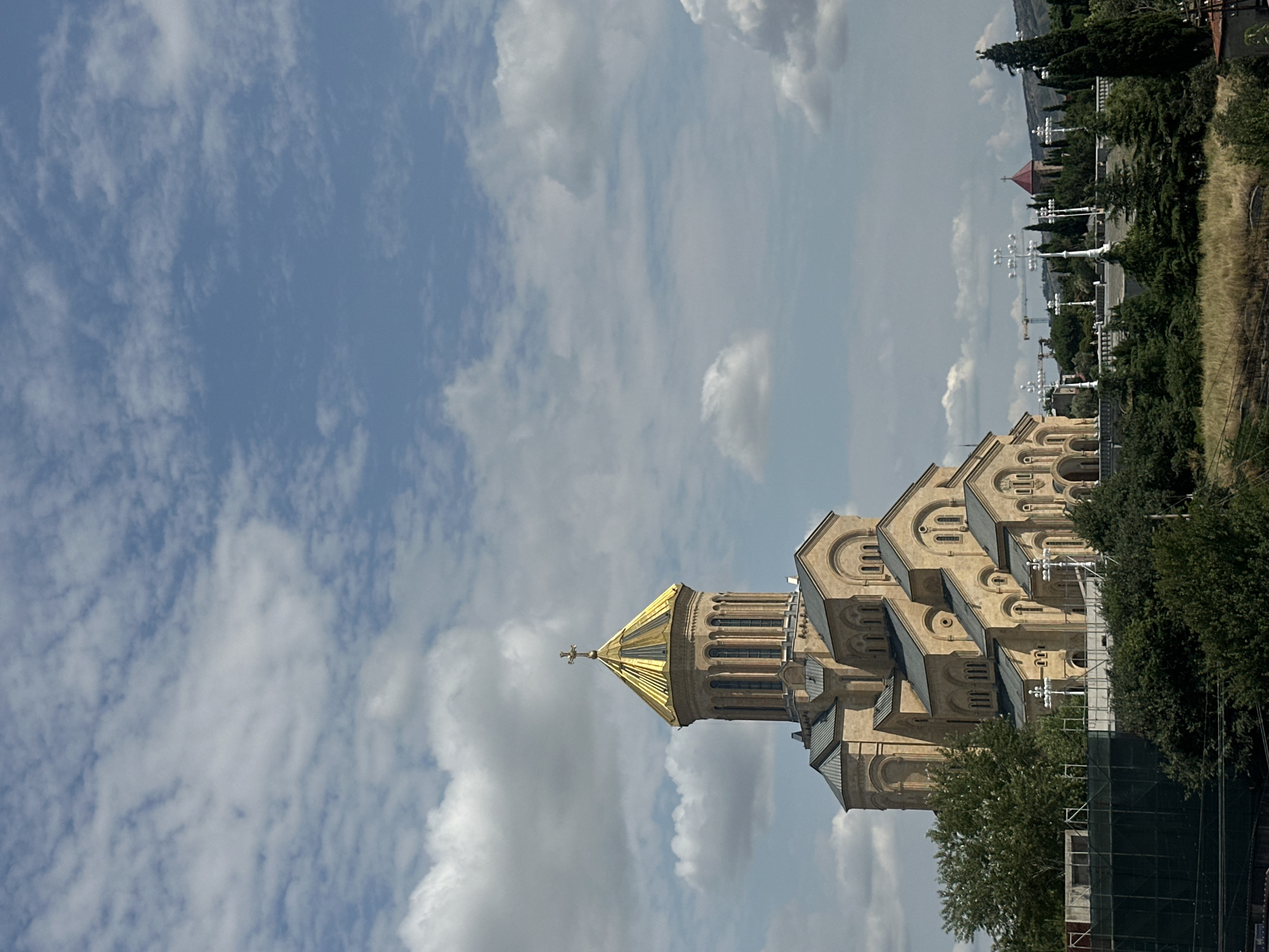 Holy Trinity Cathedral towers under a partly cloudy Tbilisi sky