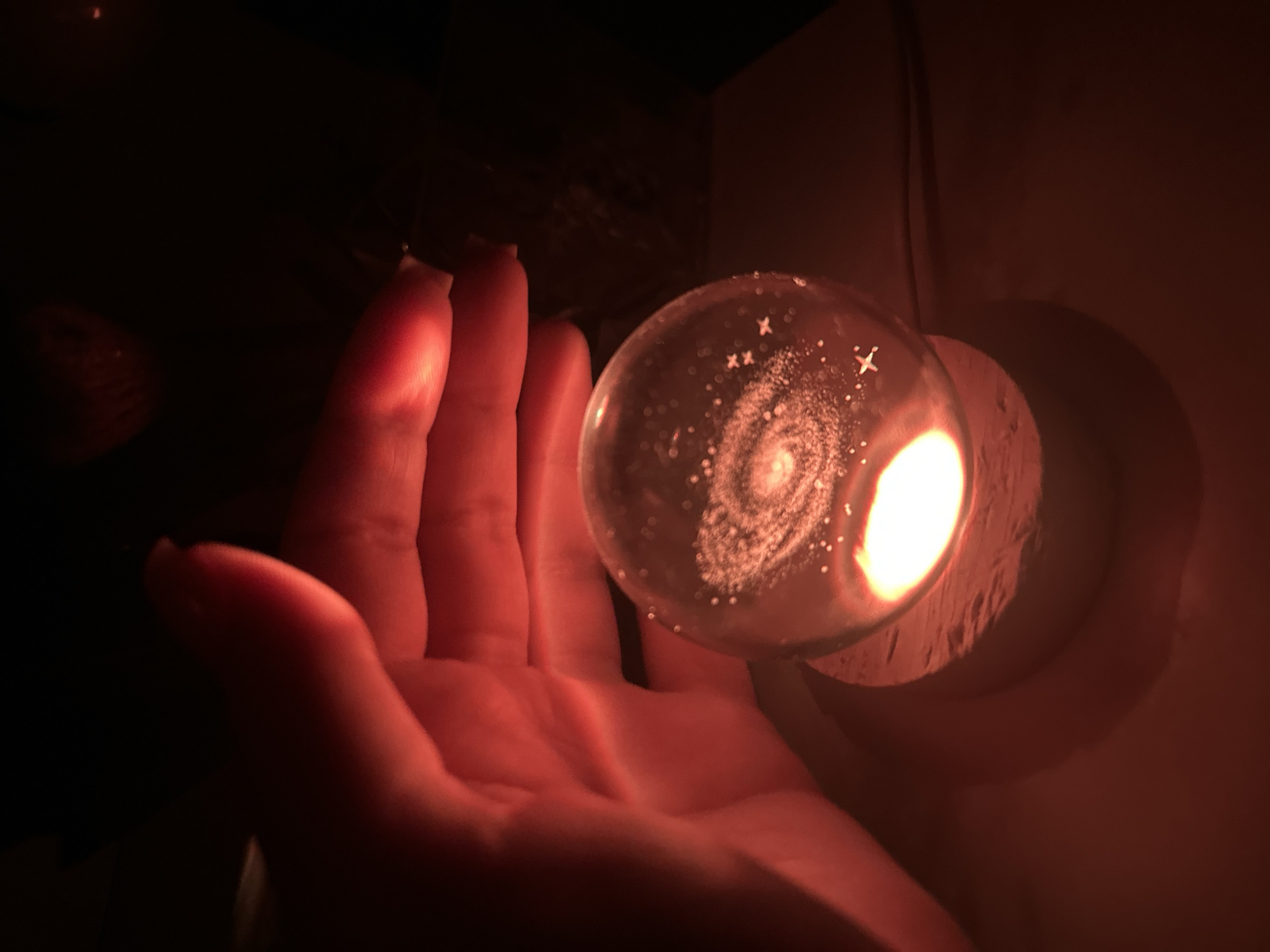 Person handles perfume bottles and glowing objects indoors