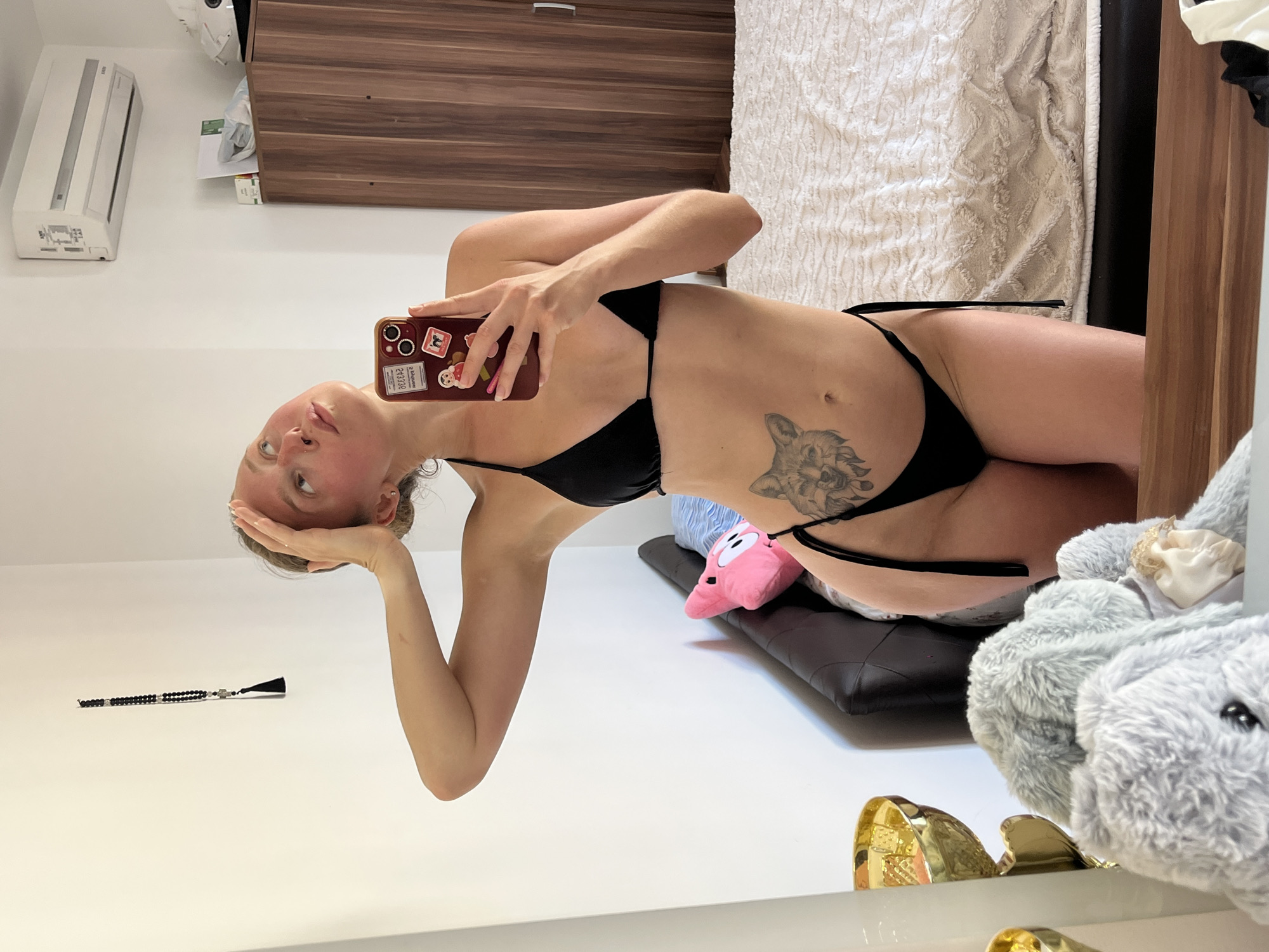 Mirror selfie in a Bečići bedroom, black bikini and wolf tattoo