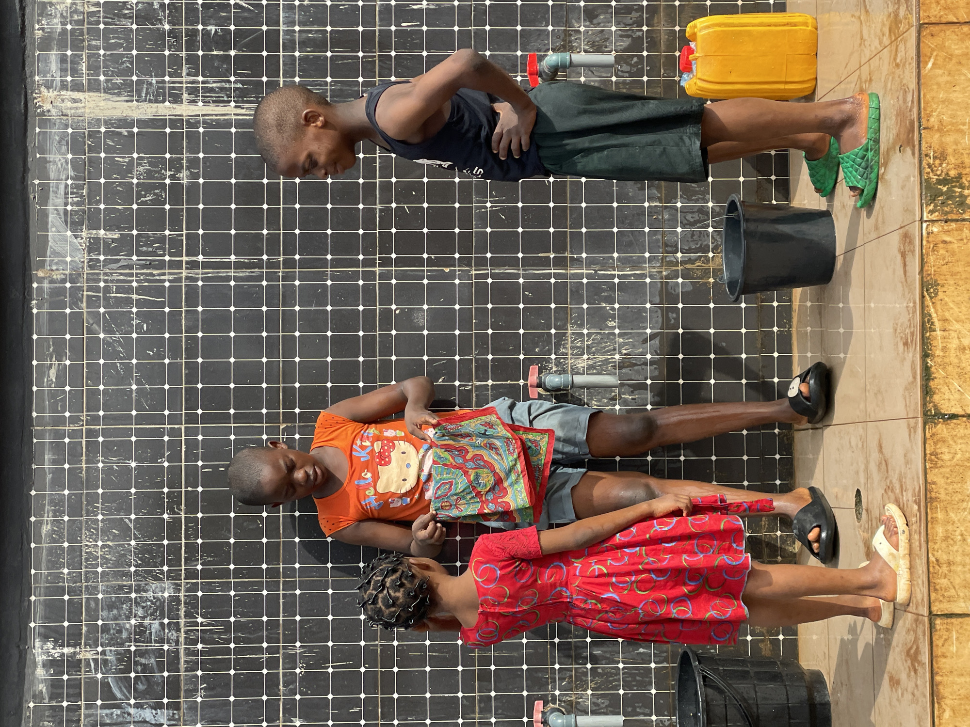 Children navigate wet surfaces and trash heap in Nkpor