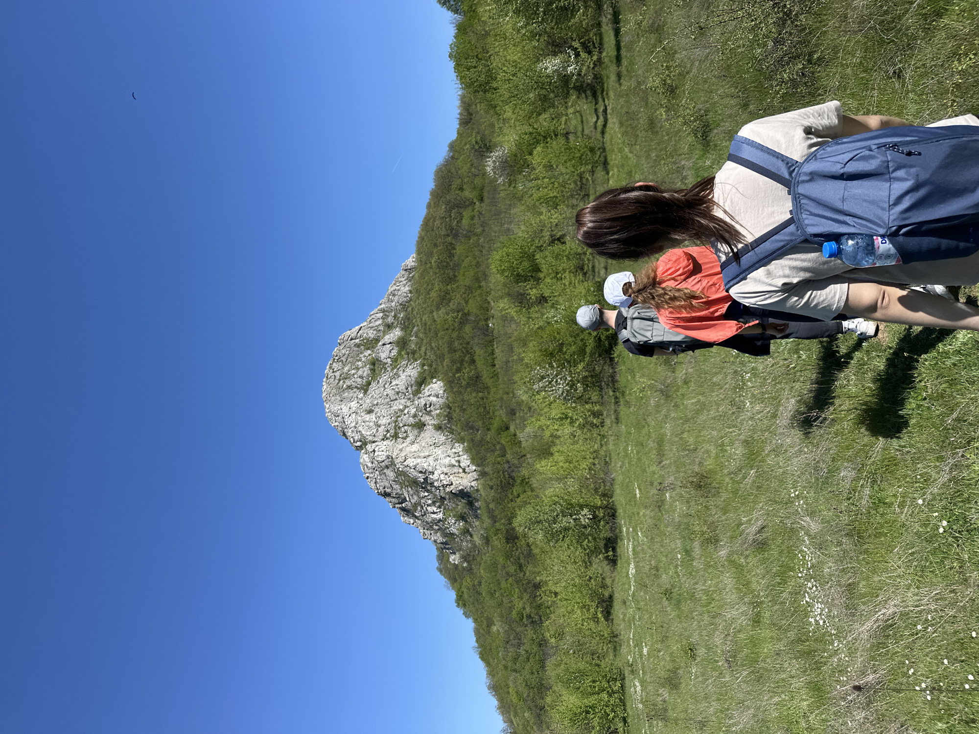 Three hikers traverse grassy field near Bilka, Bulgaria