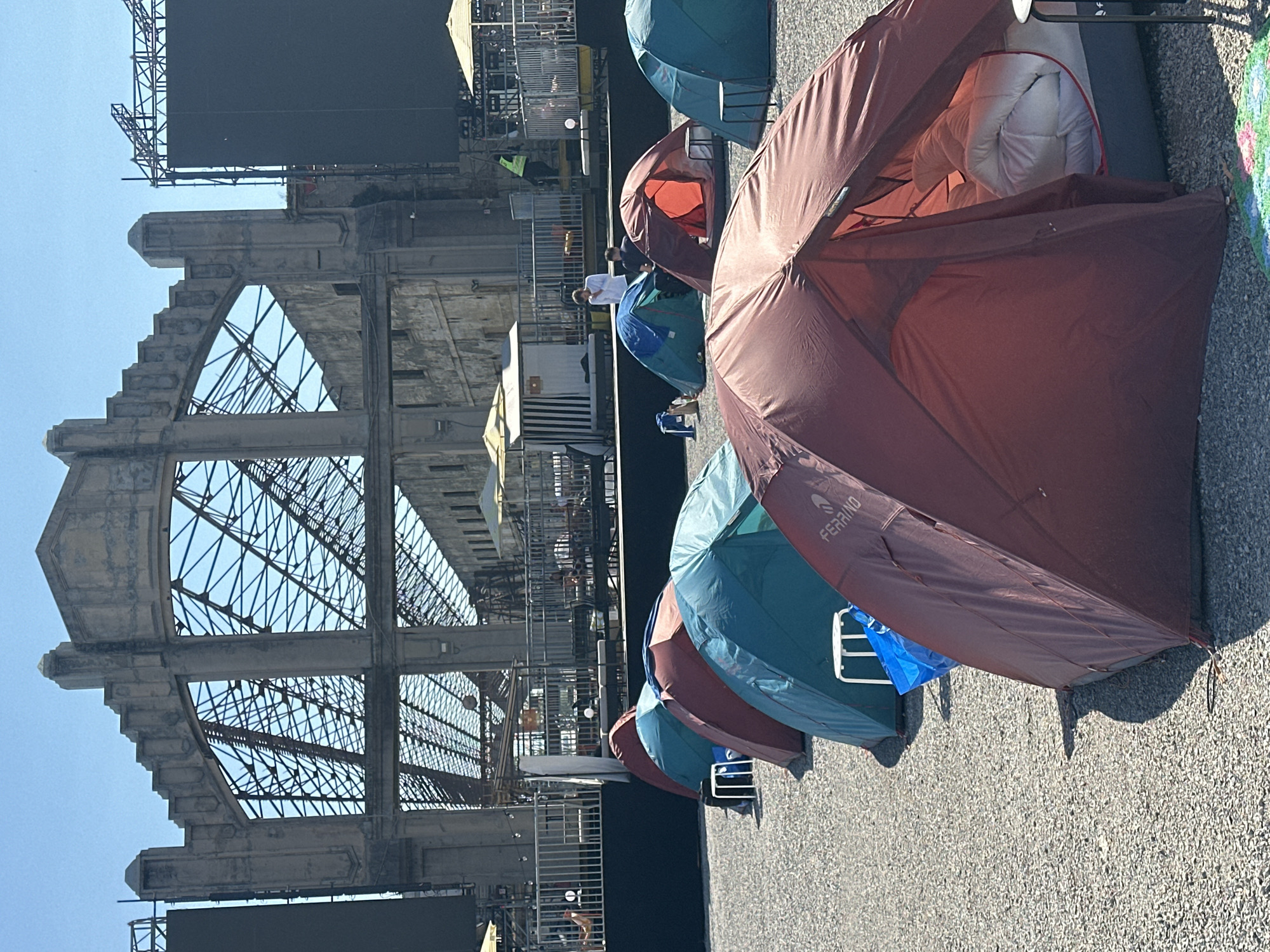Camping tents with gear spotted on paved surface in Milan