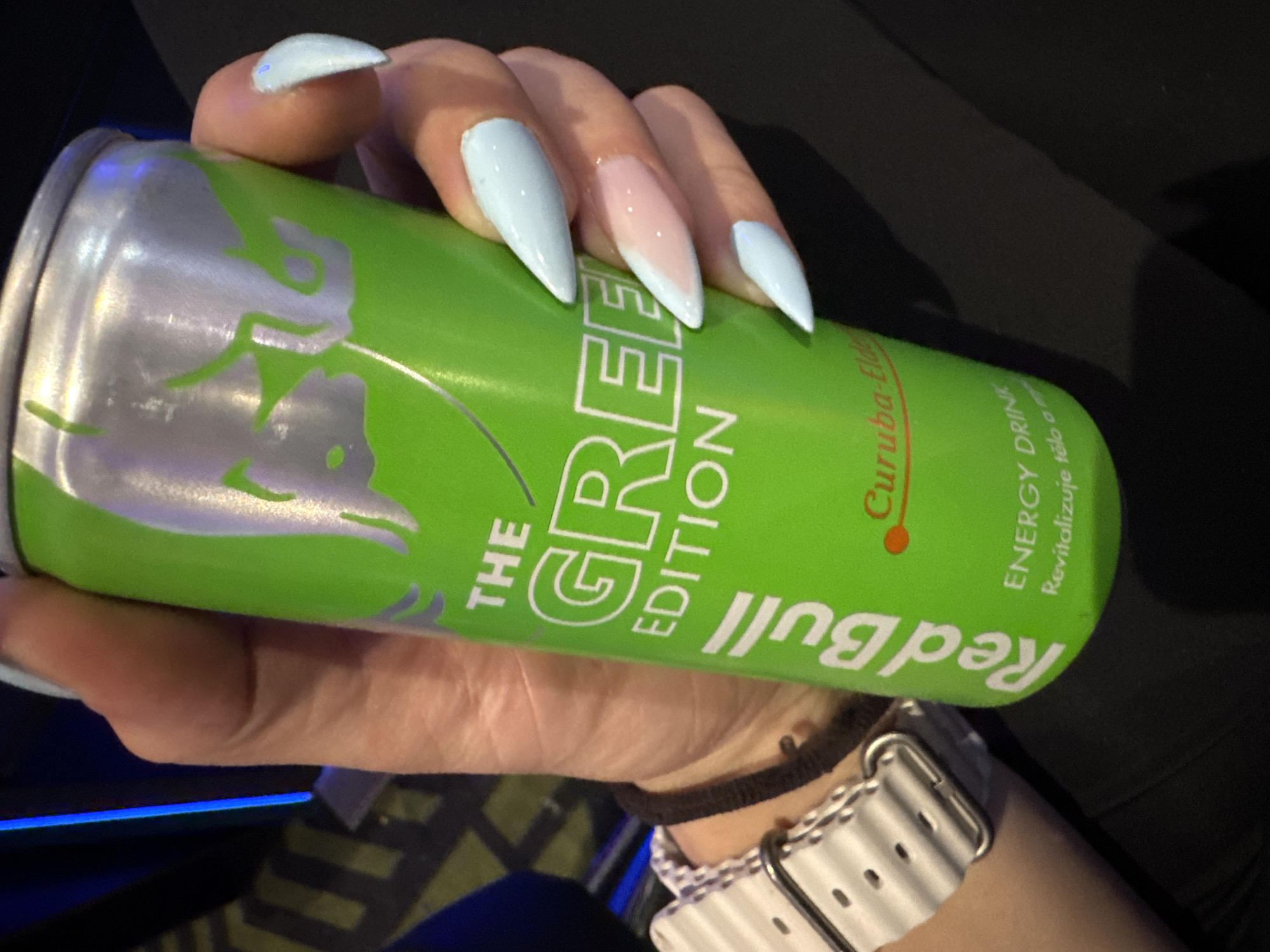 Person with blue nails, energy drink, velvet bag documented