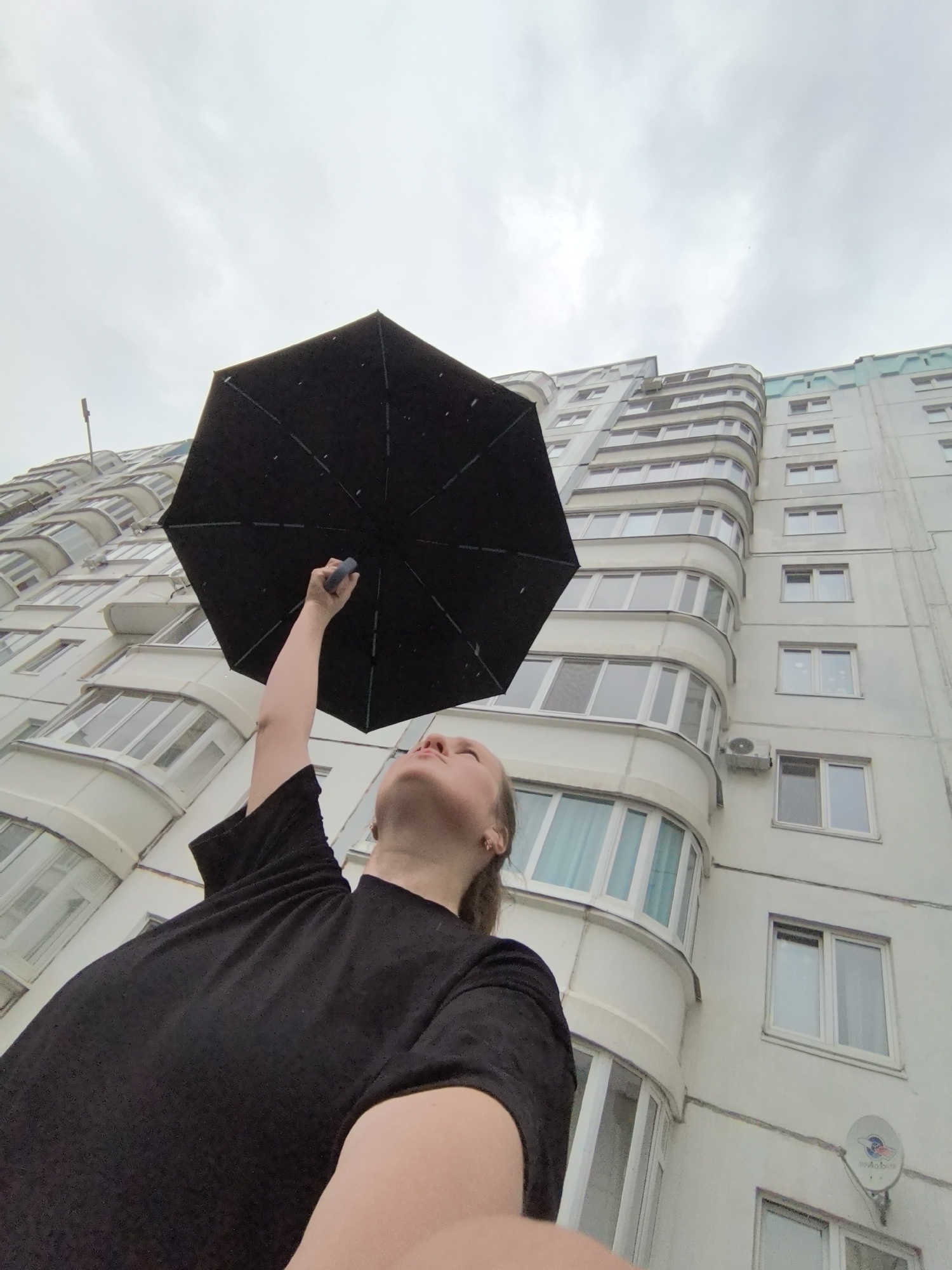 Person holds umbrella skyward in cloudy Froly, Russia