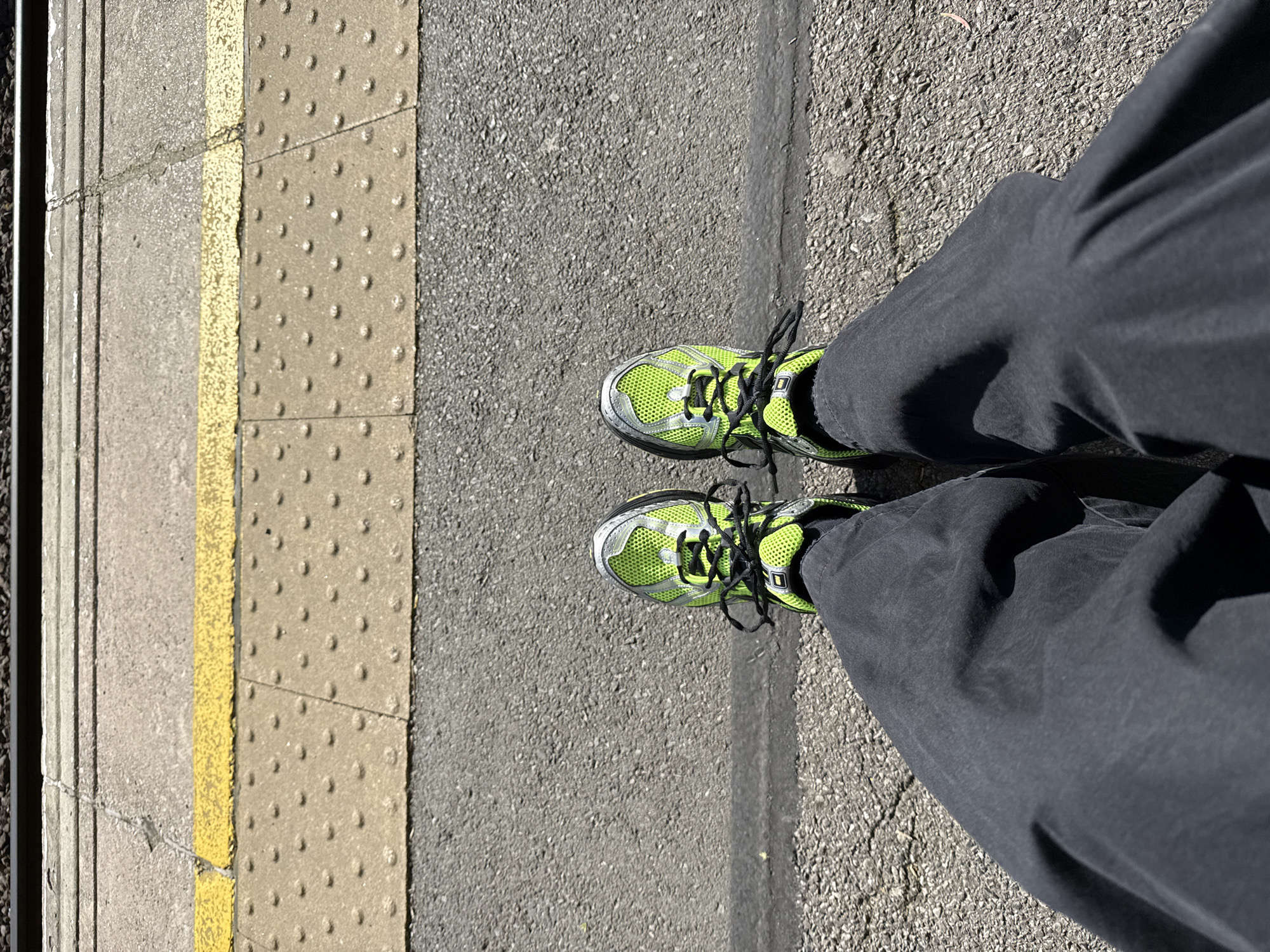 Commuter in green sneakers waits on London train platform