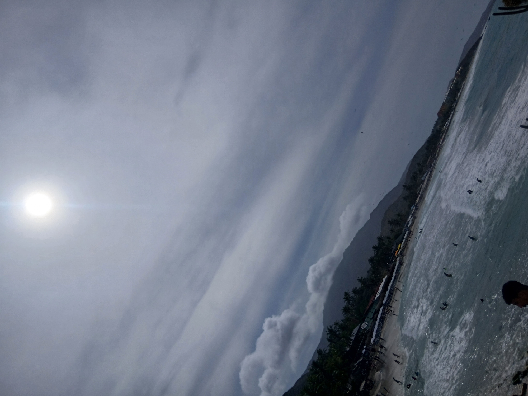 Beachgoers gather at Playa Parguito under cloudy Venezuelan skies
