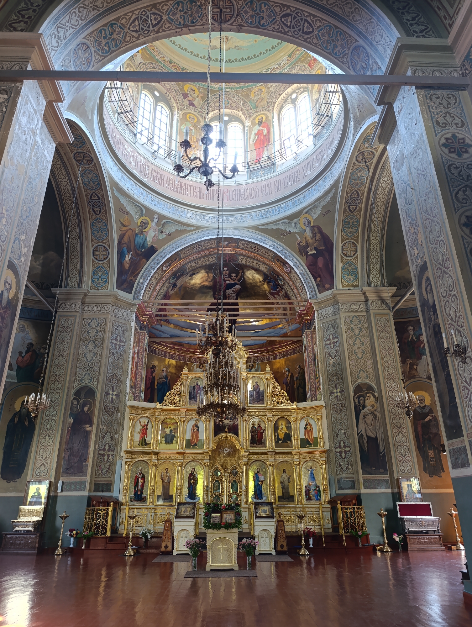 Inside an ornate church with murals, gold tones, and a grand altar
