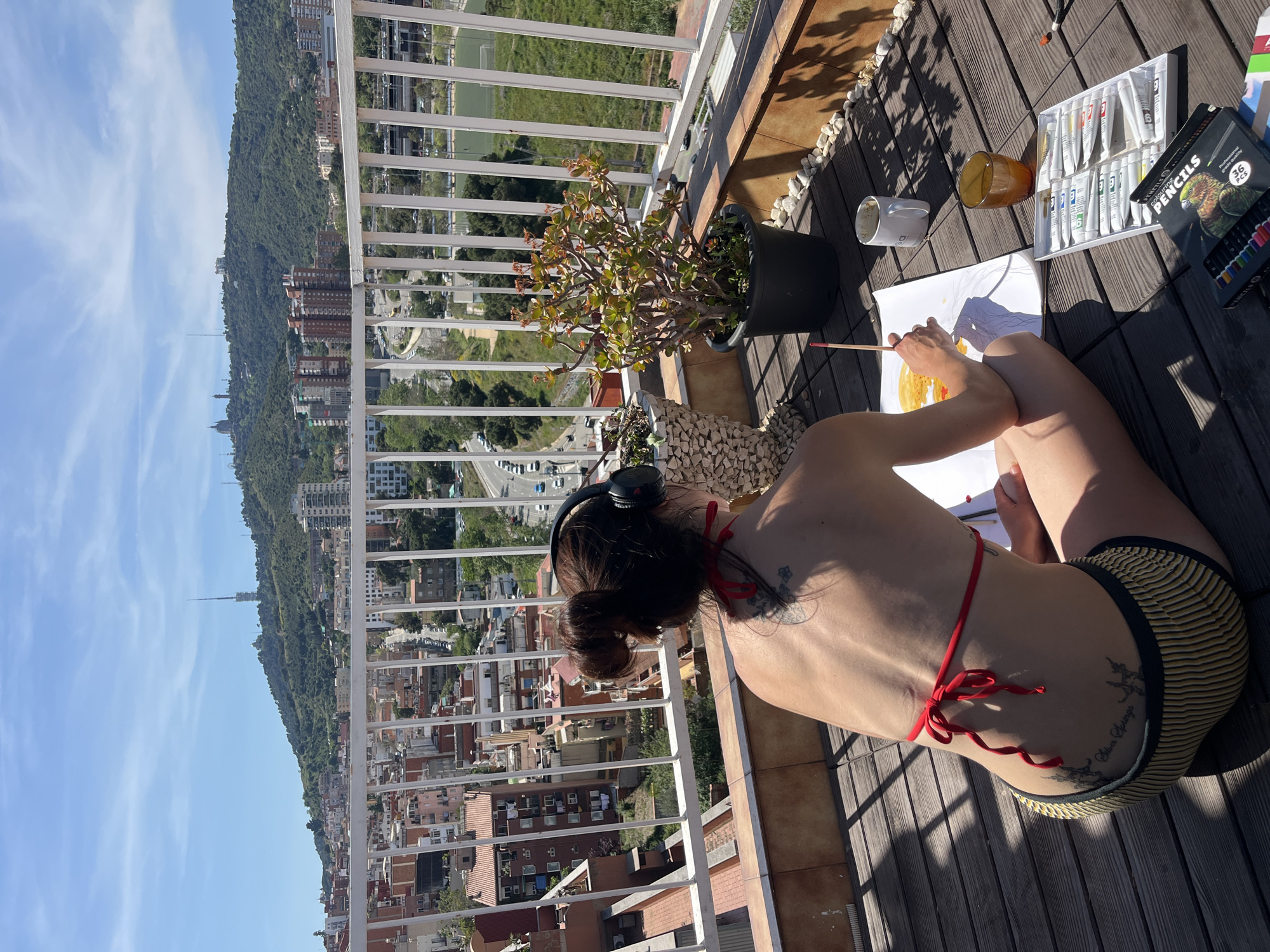 Woman paints from balcony overlooking Barcelona cityscape
