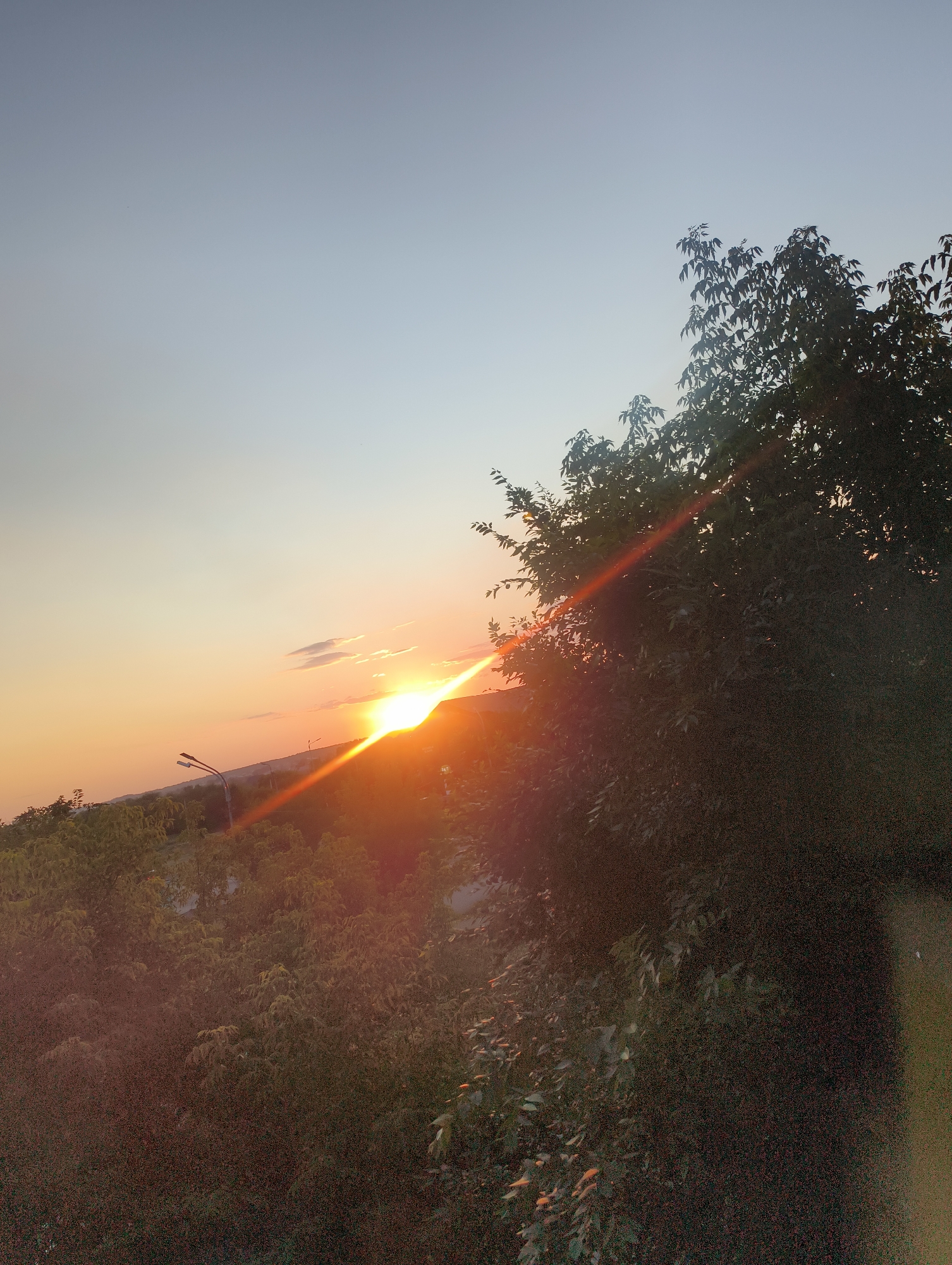 Sun tracking from midday glare to dusk over a Cyrillic-script city