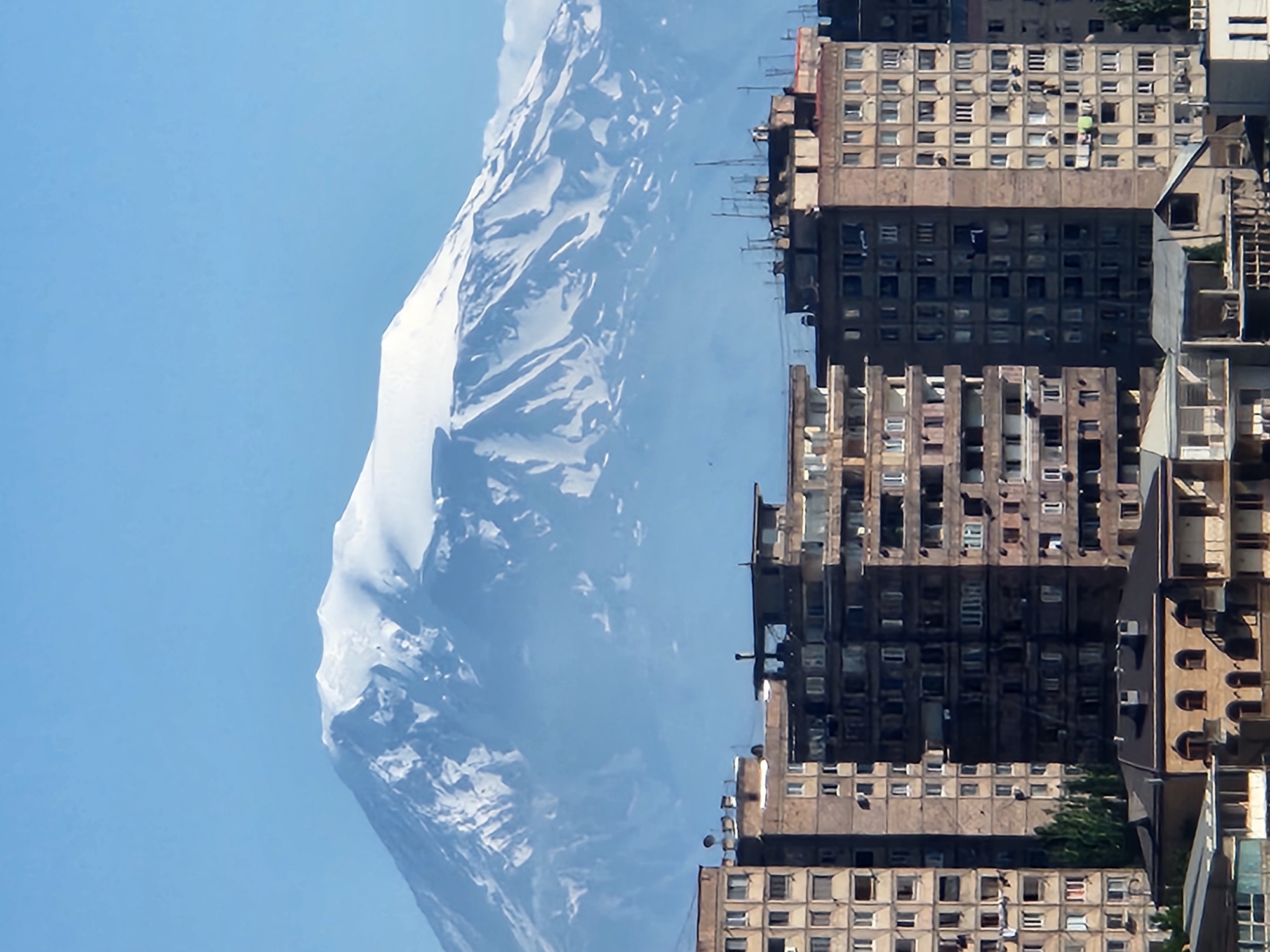 Urban buildings sit in front of a snow-capped mountain range
